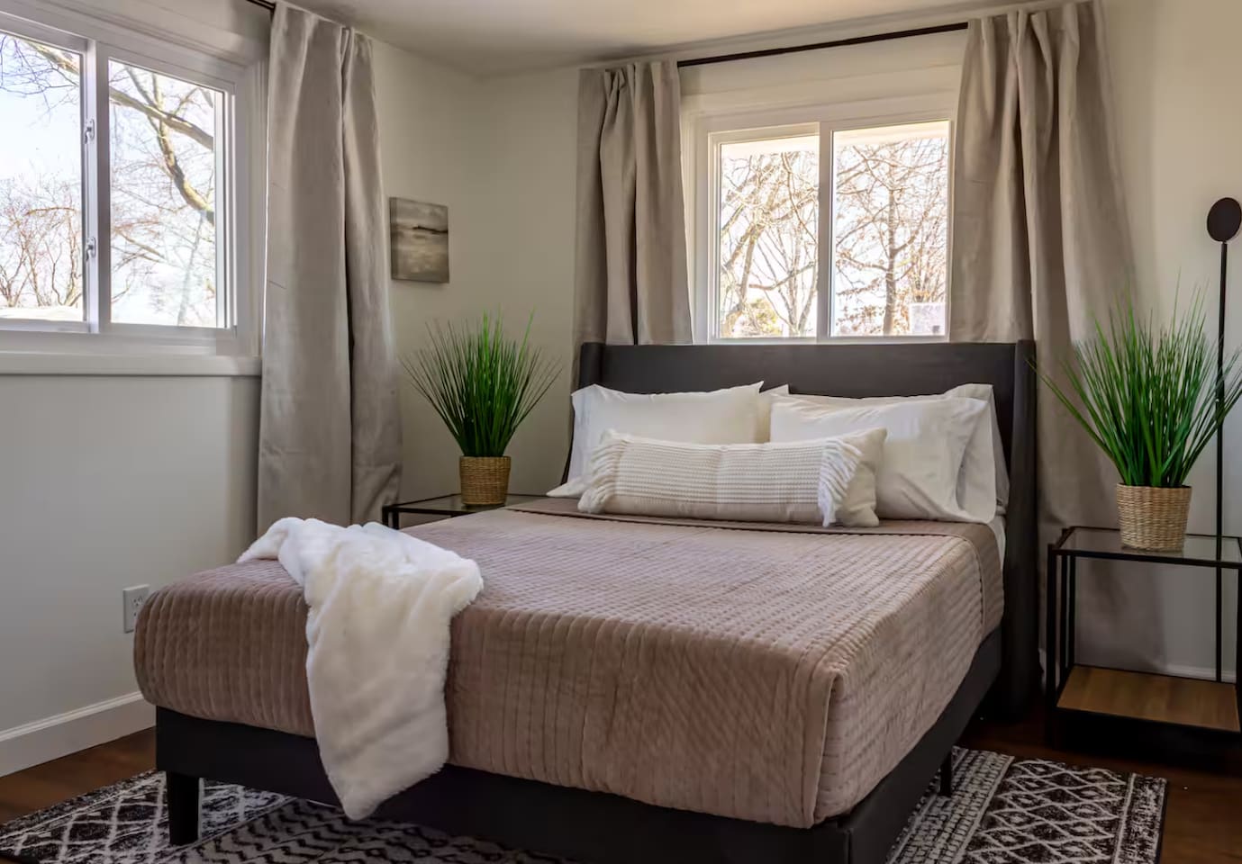 Natural light pours through two windows, framing a bed made for slow mornings.