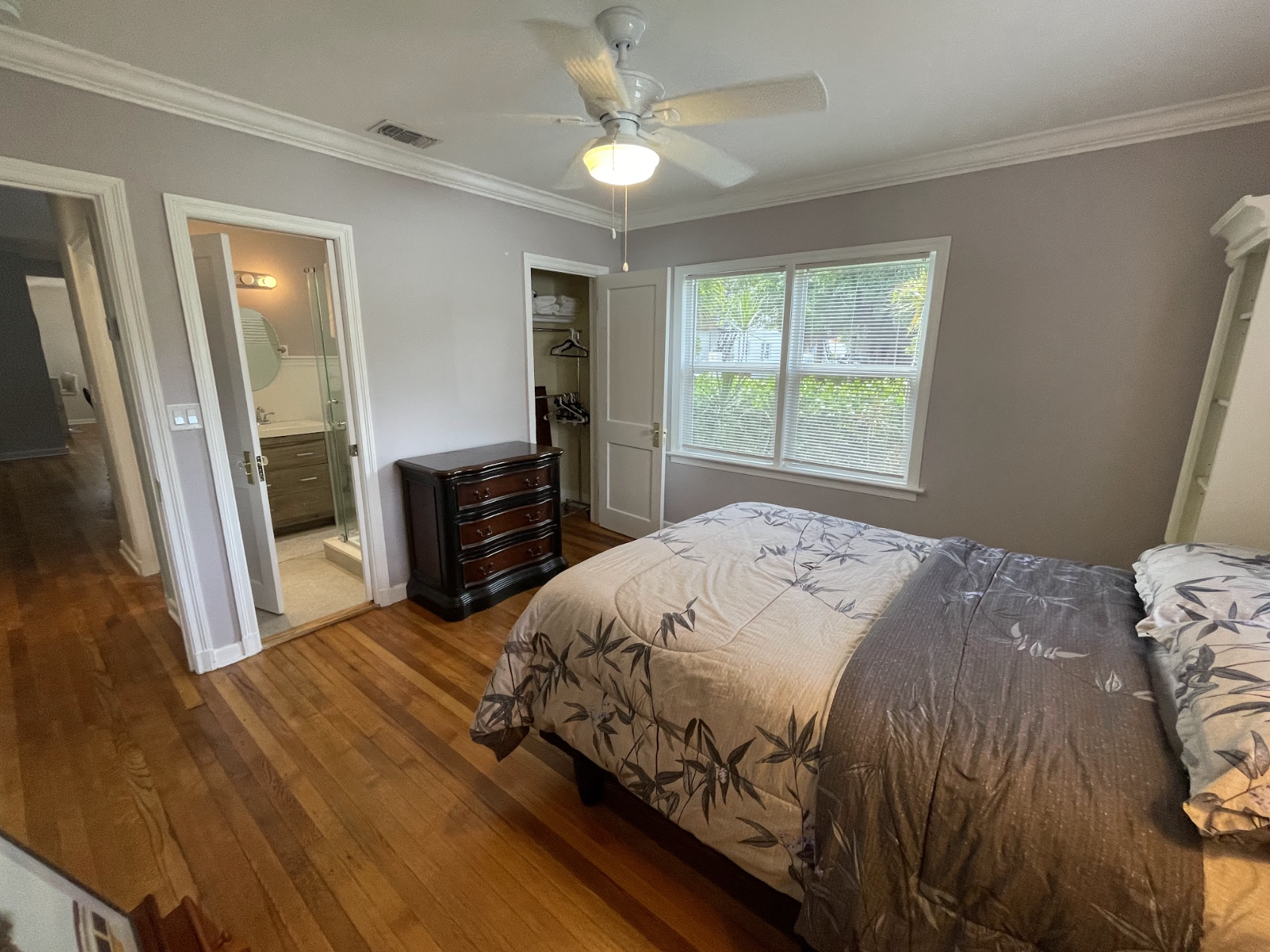The second bedroom features a queen-zied bed and a stylish painter's floor stand.