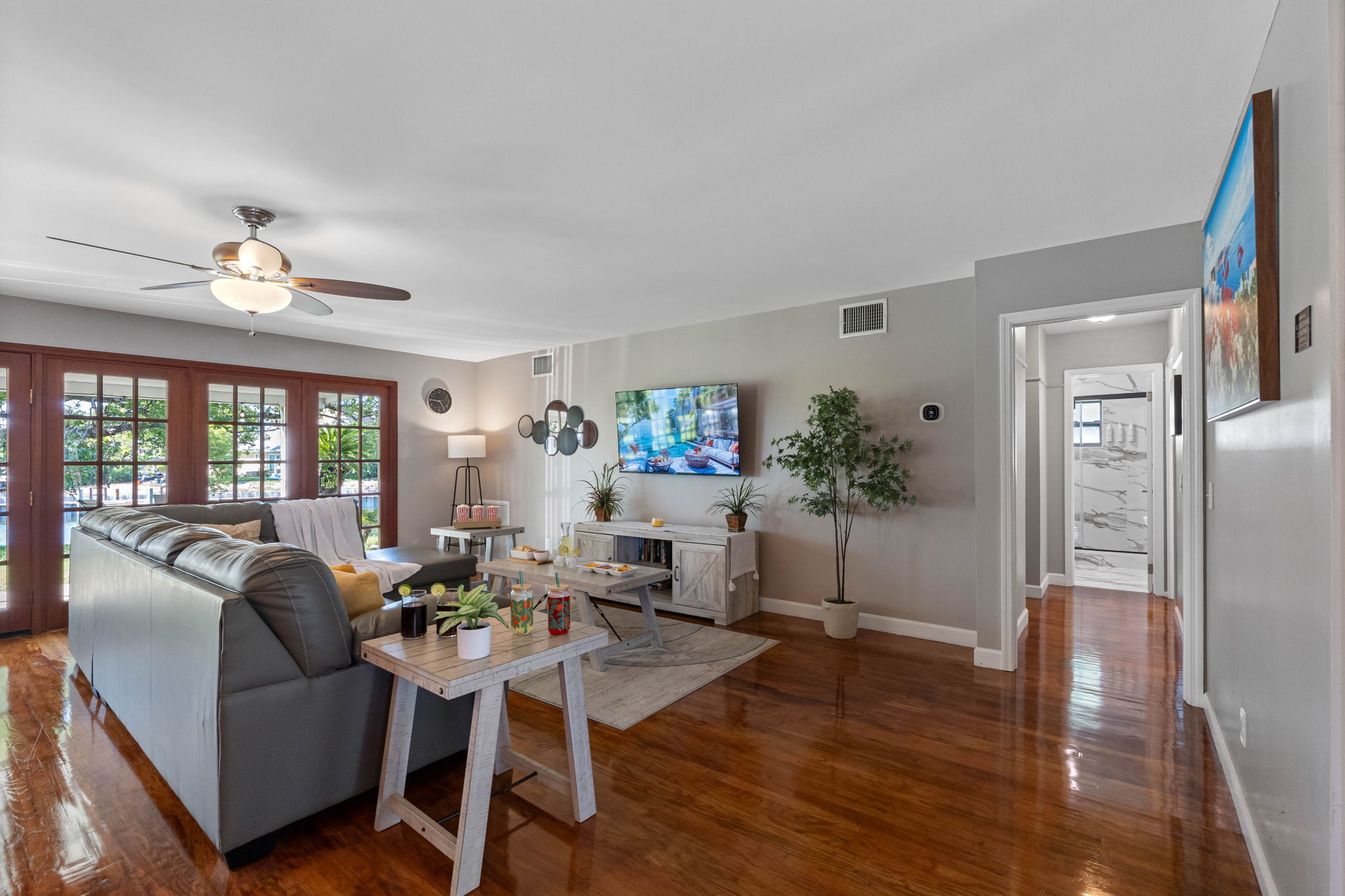 The abundance of glass doors allows sunlight to stream through, highlighting the rich wood floors and soft gray walls.