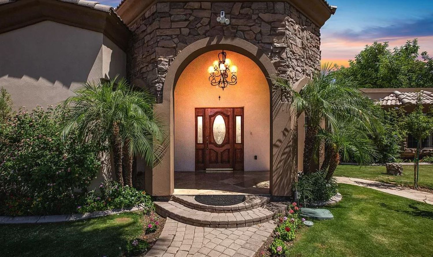 Make a grand entrance into your serene retreat, where lush landscaping, elegant stonework, and warm lighting set the tone for a relaxing stay.