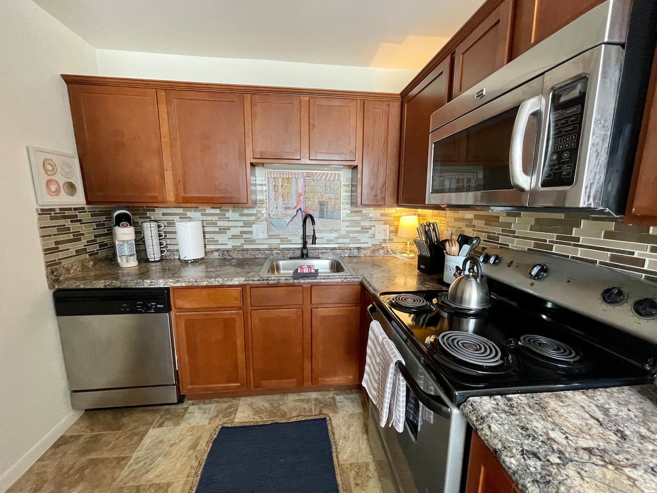 Fully equipped kitchen with stainless steel appliances, rich wood cabinetry, and stylish backsplash. Enjoy the convenience of a modern stove, microwave, dishwasher, and all the essentials needed to cook and dine comfortably during your stay.