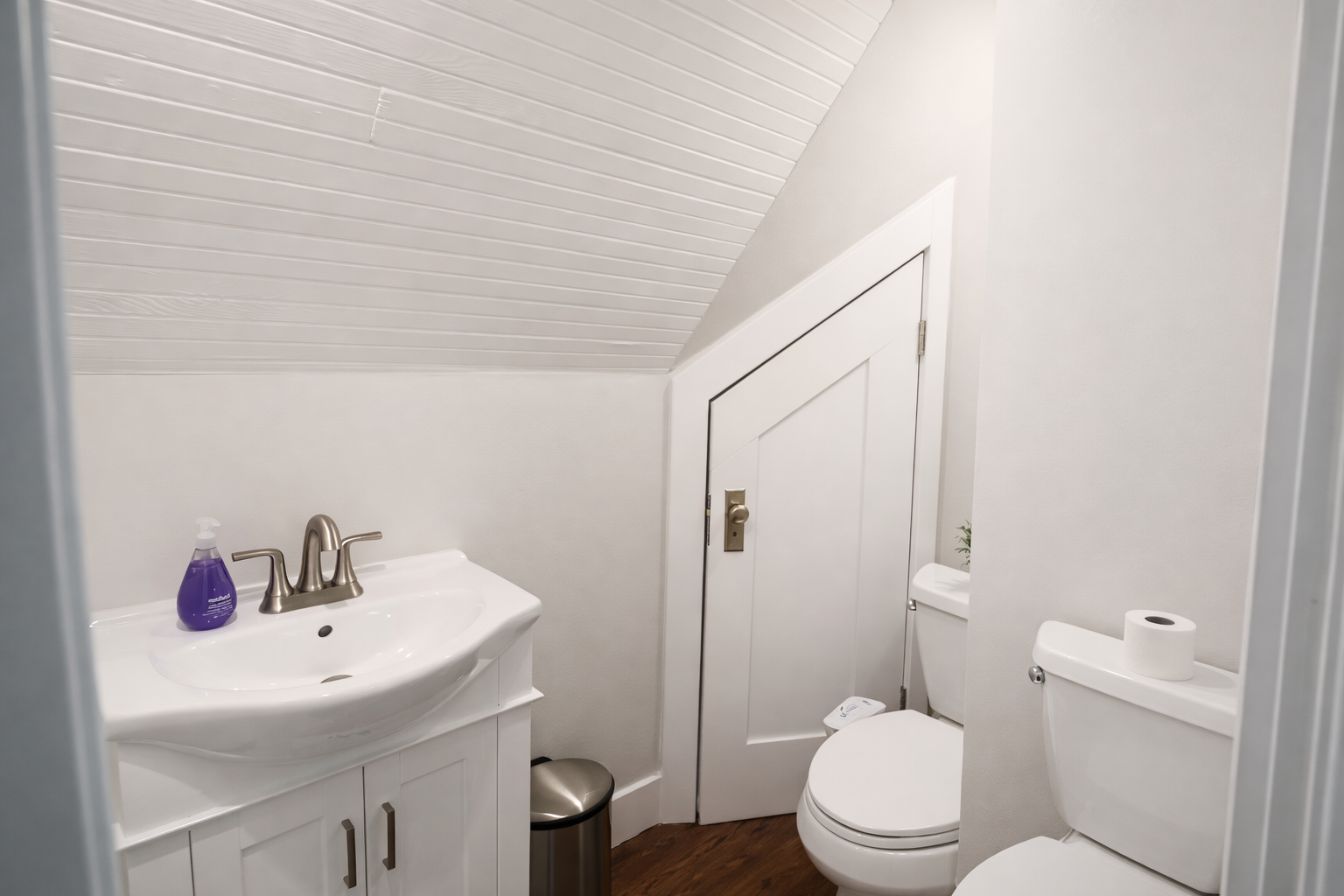 A convenient half-bath tucked away with classic beadboard ceilings and a crisp white vanity.