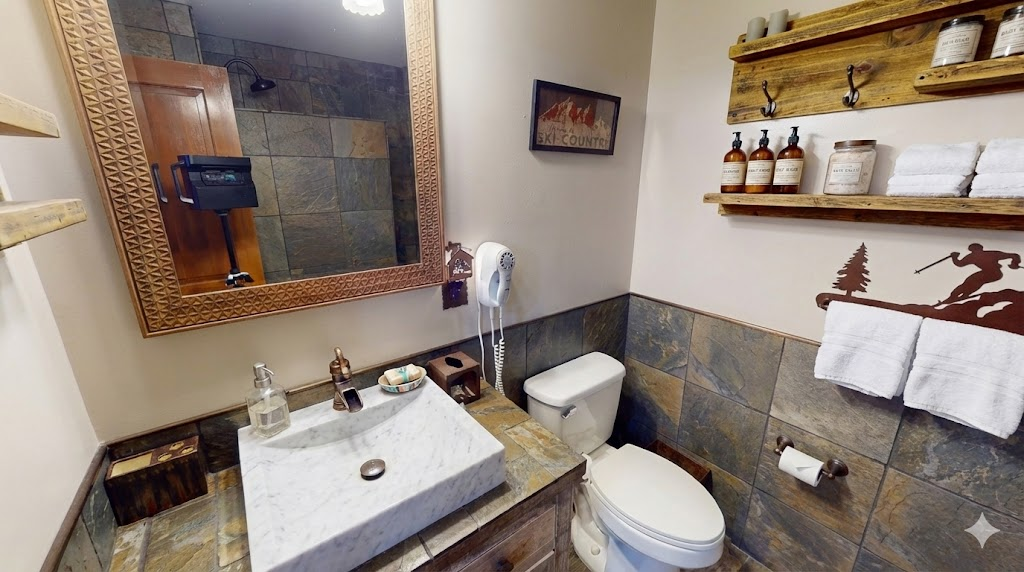 Mountain-chic bathroom with rustic stone tiles and modern fixtures — unwind after a day on the slopes.