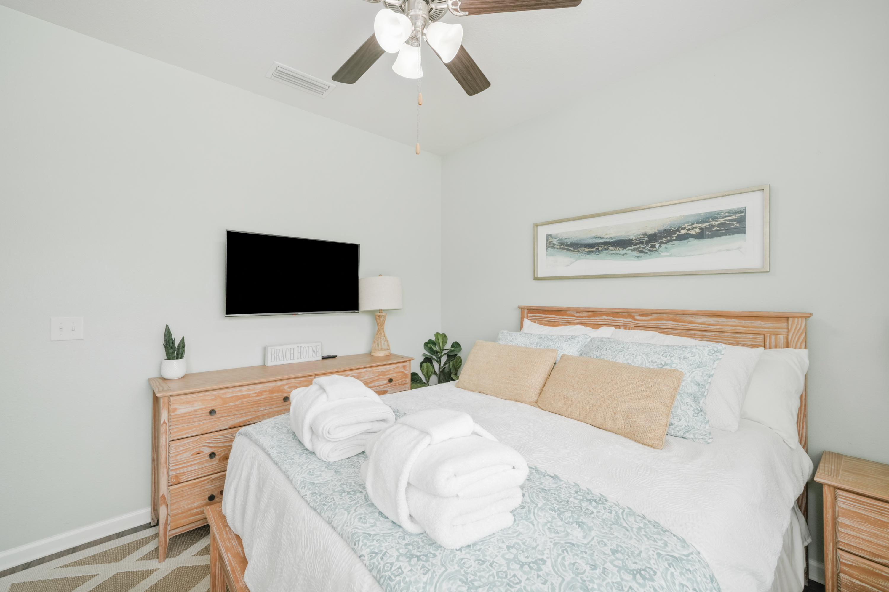 Bedroom 3: Queen bedroom featuring ceiling fan, bedside lamp, plush linens, dresser and Smart TV