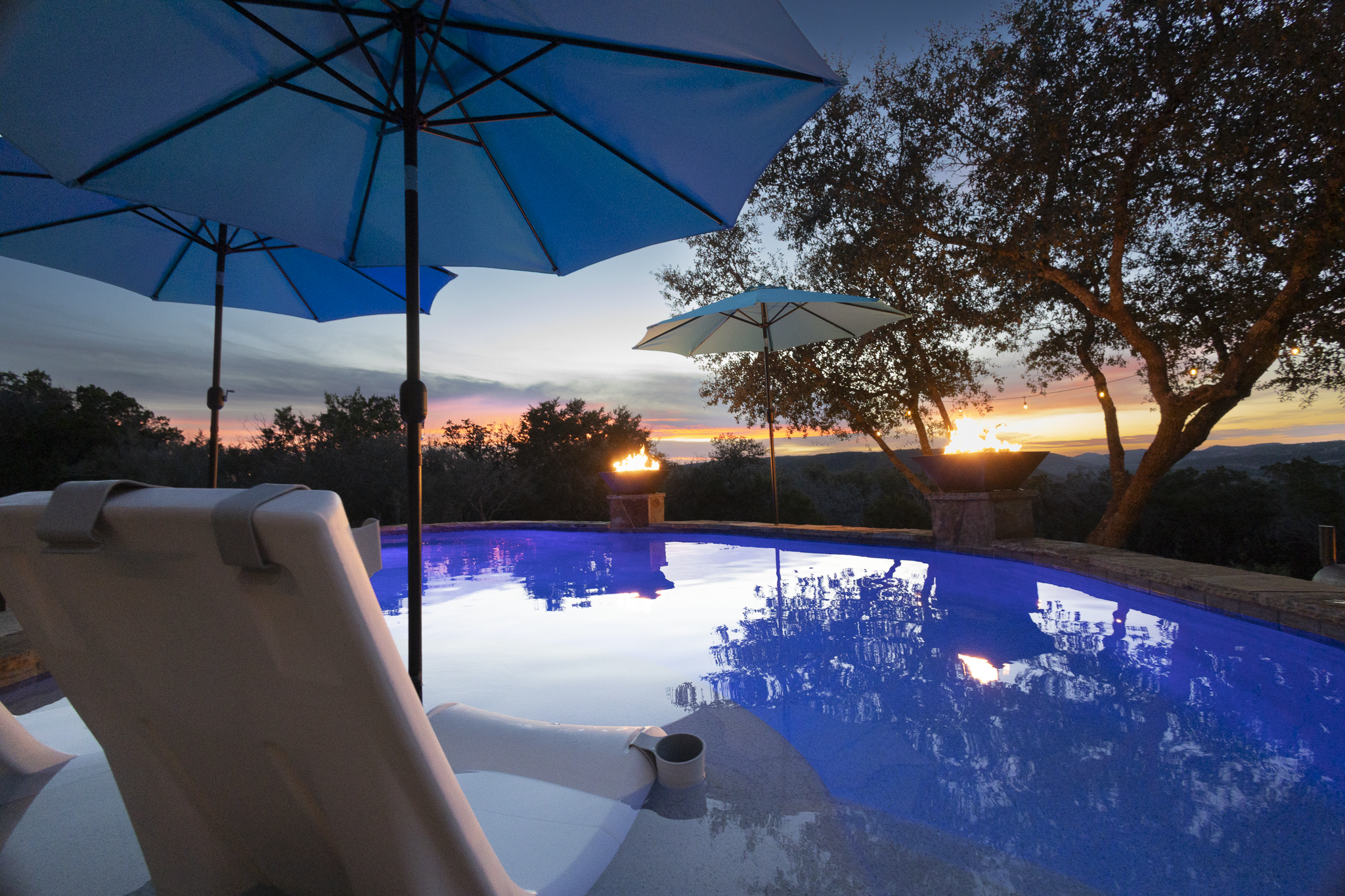 Heated year-round pool at sunset with fire bowls and Hill Country views