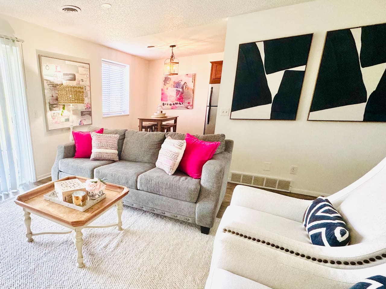 Bright and inviting living space with colorful floral decor, comfortable seating, and a playful area rug. Sliding glass doors open to scenic views, filling the room with natural light—perfect for morning coffee or evening unwinding.