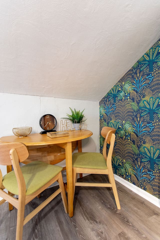 Enjoy a cozy meal or a morning coffee in this charming dining nook. The stylish wooden table and chairs are complemented by vibrant wallpaper, creating a delightful space to start your day. This inviting corner adds a touch of personality and warmth 