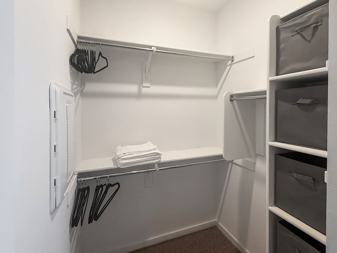 Walk-in closet with shelves, rods, hangers, and folded towels