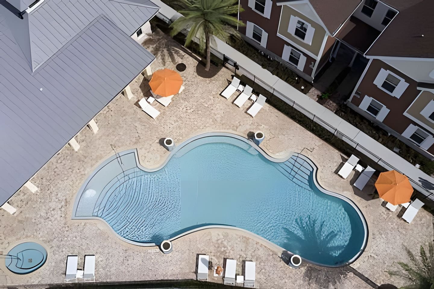 Aerial view of the pool area, featuring a jacuzzi, shaded umbrellas, and plenty of lounge space.