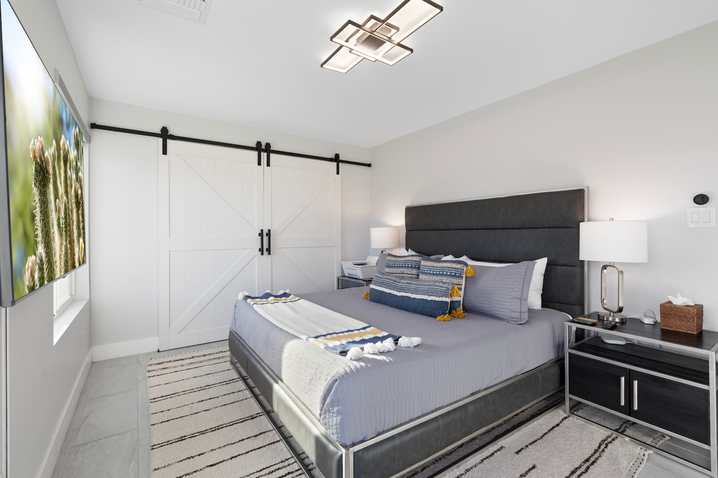 Rest easy in this king-size bed framed by a padded headboard and paired with crisp white barn doors for a clean, rustic-modern vibe.
