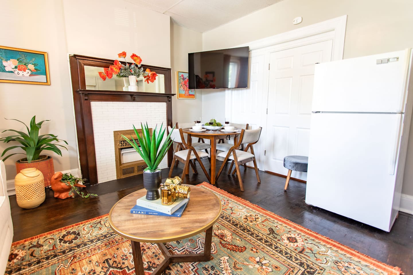 Spacious living and dining area with a stylish center table positioned in front of the TV, creating a cozy focal point, complemented by a fridge nearby for added convenience.