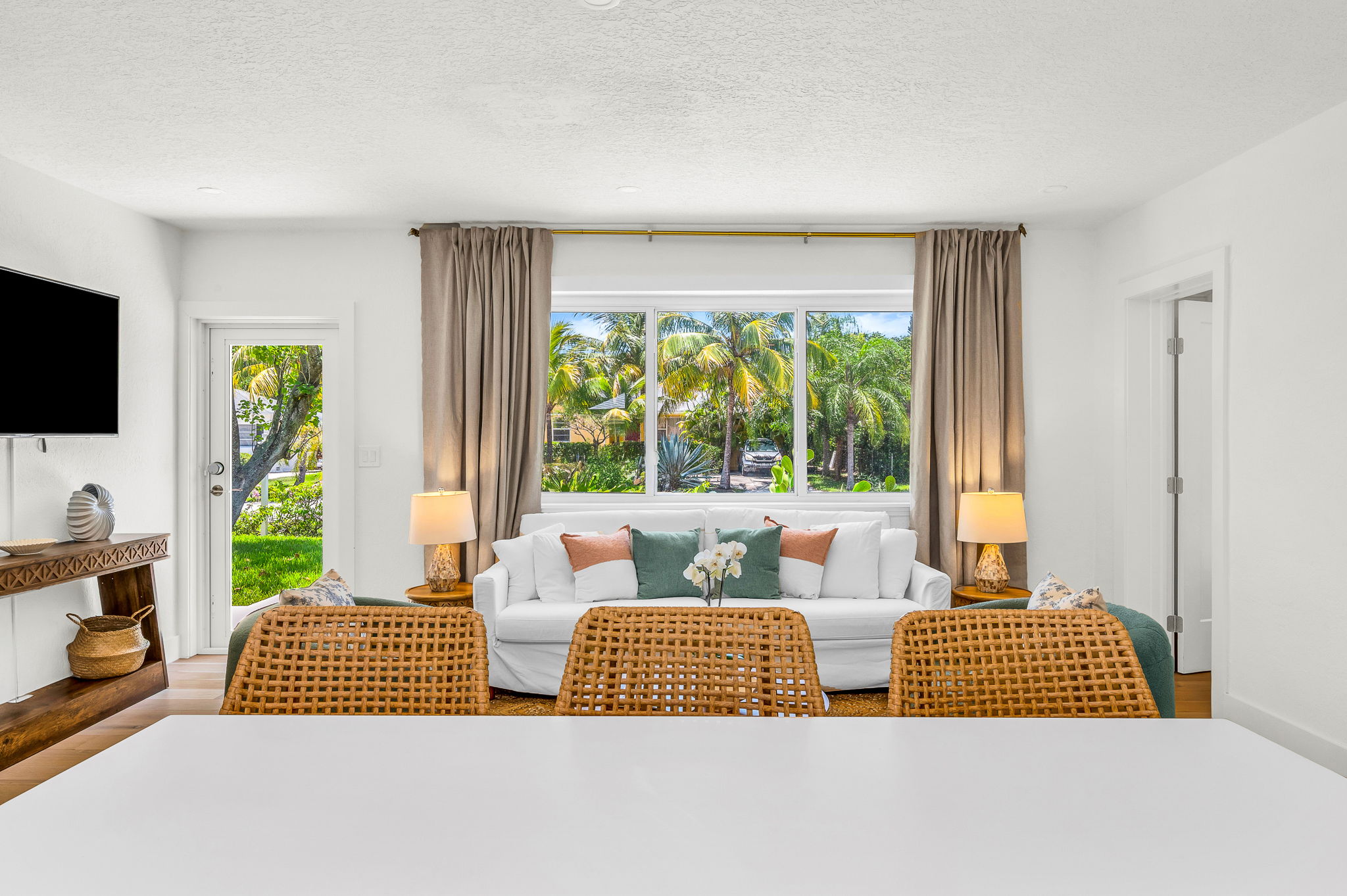 Bright and airy living space featuring designer furnishings, tropical views through oversized windows, and a seamless connection to the lush outdoors—perfect for relaxing in style after a day at the beach.