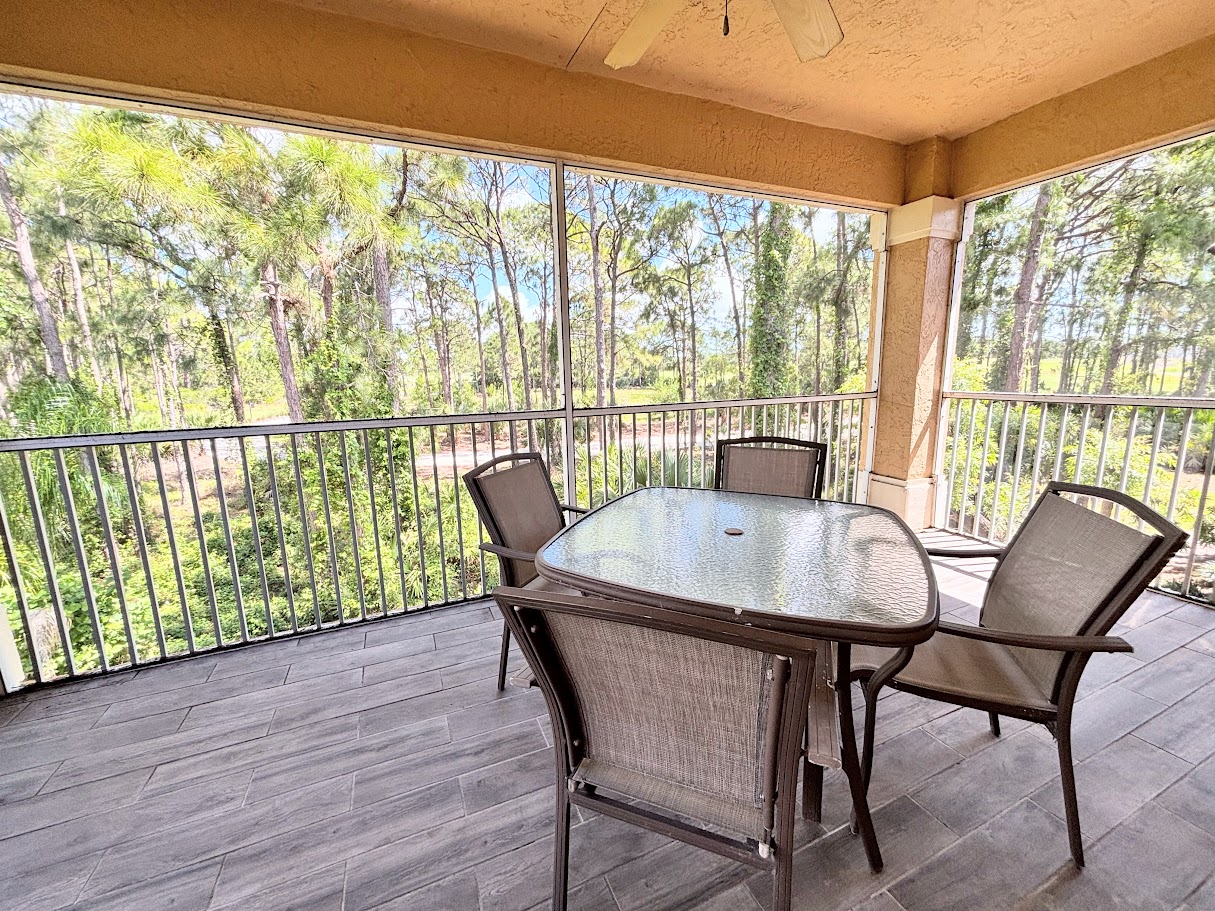 Private screened balcony with outdoor dining space and peaceful views of the surrounding trees.