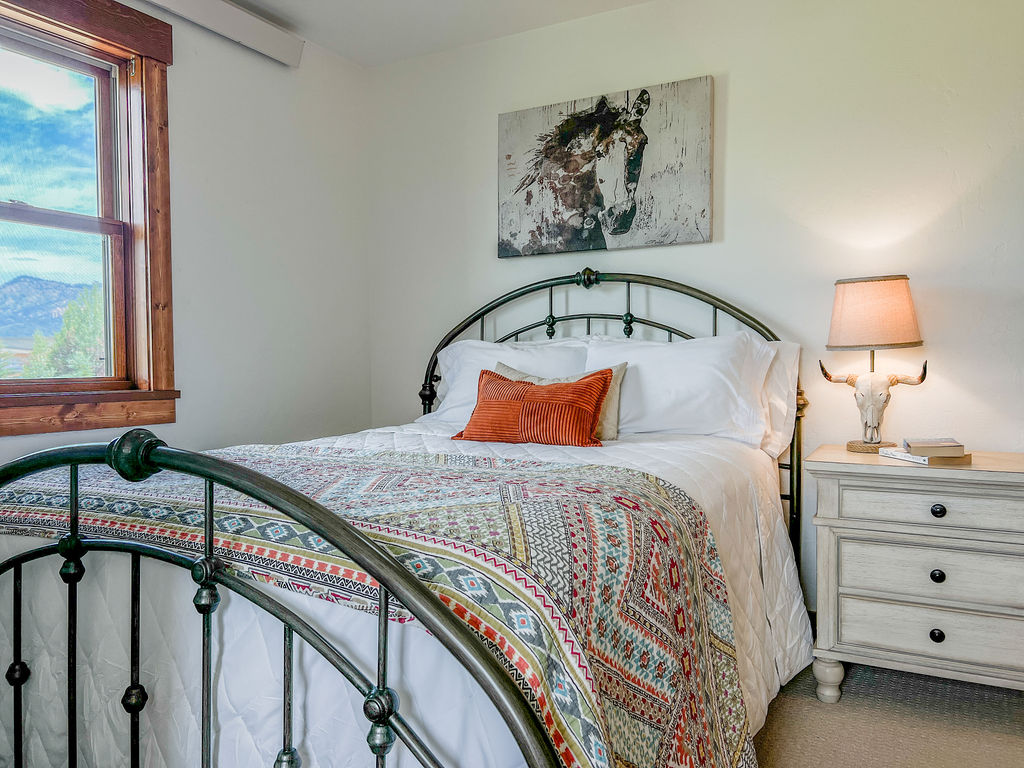 Enjoy this quiet, cozy room featuring a queen bed, large dresser, hanging closet, and mountain views!