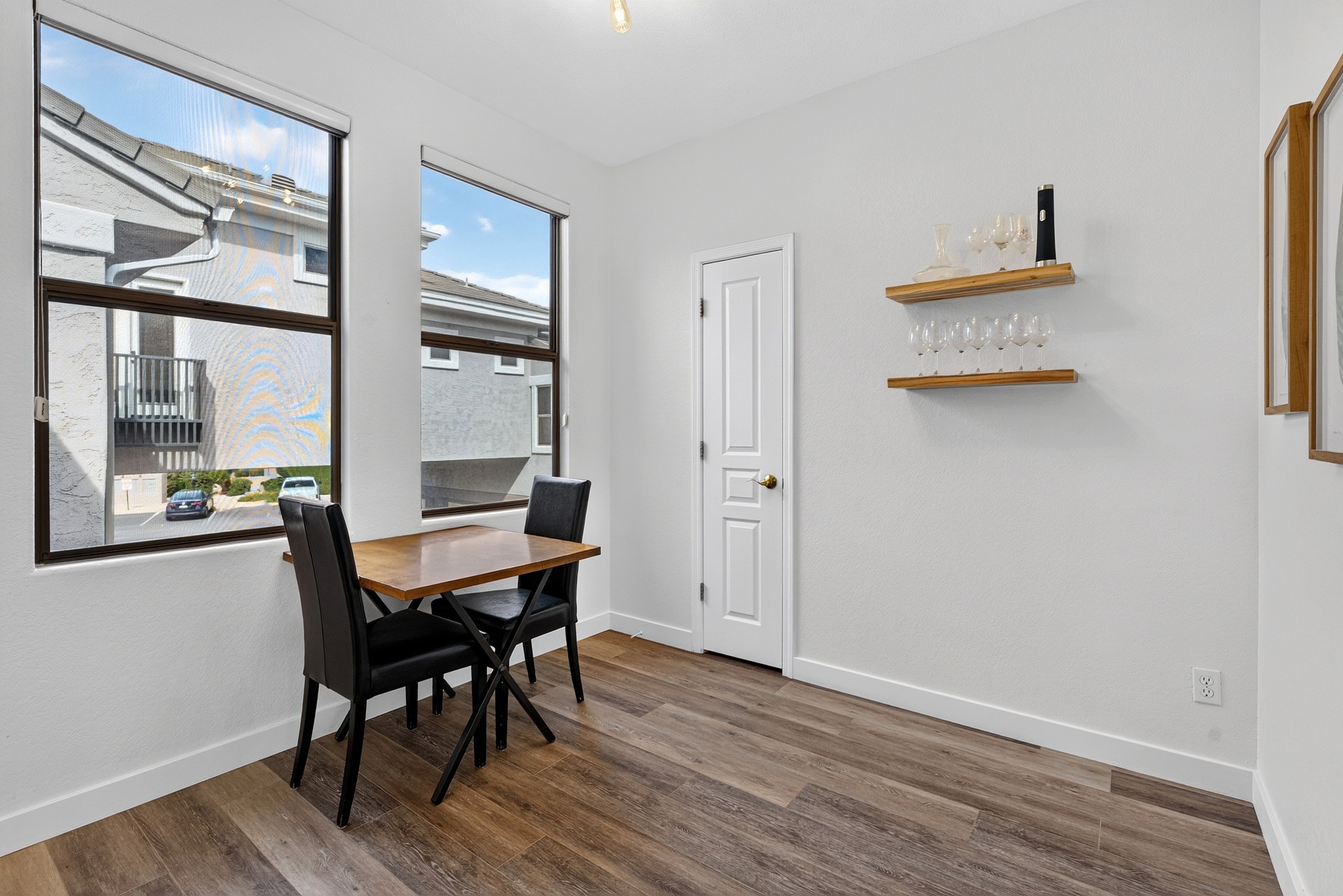 Table seating, window light, and wall shelves for a simple spot to eat, work, or plan the day.
