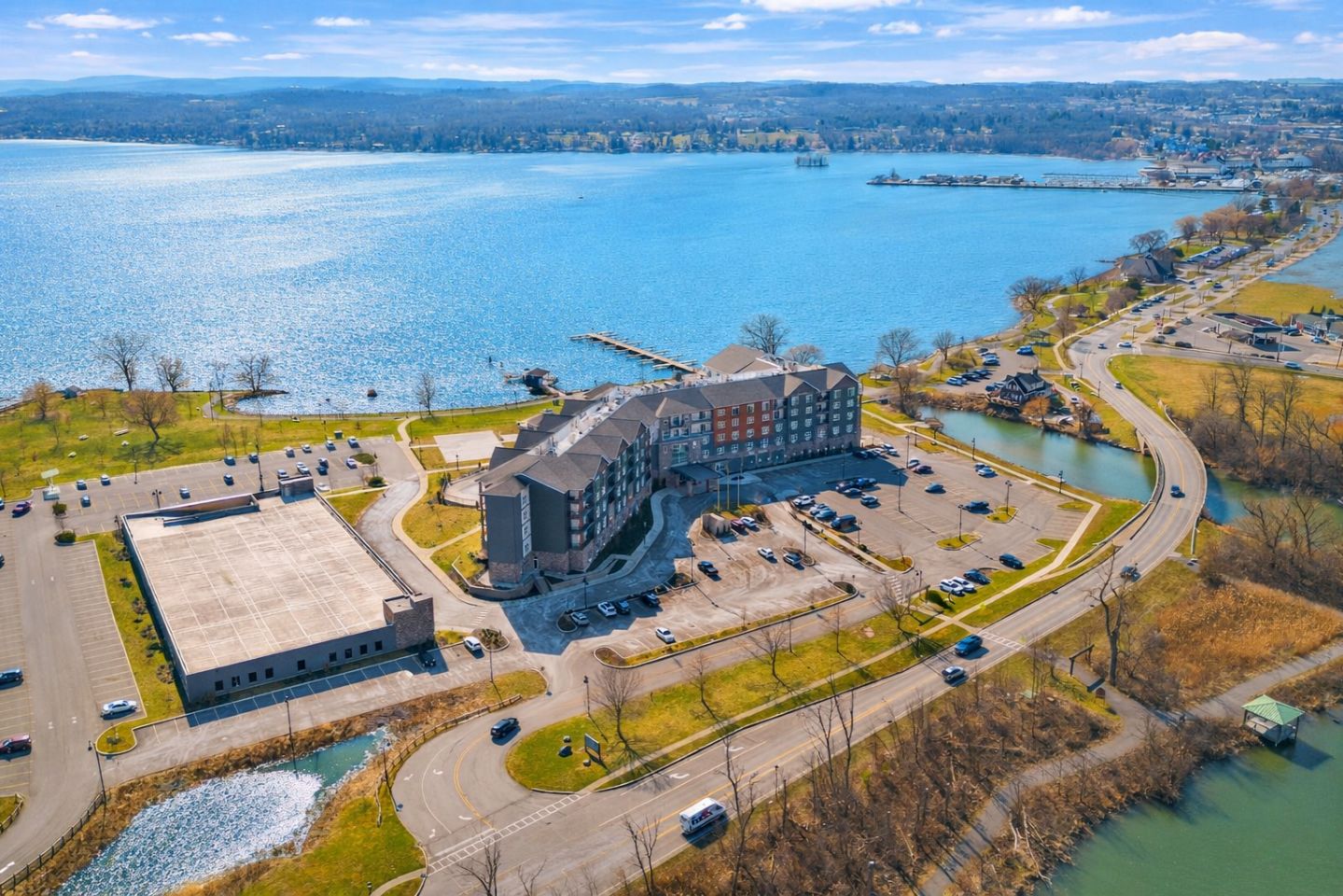 Arial view of lakeside apartment complex with ample parking and scenic views.