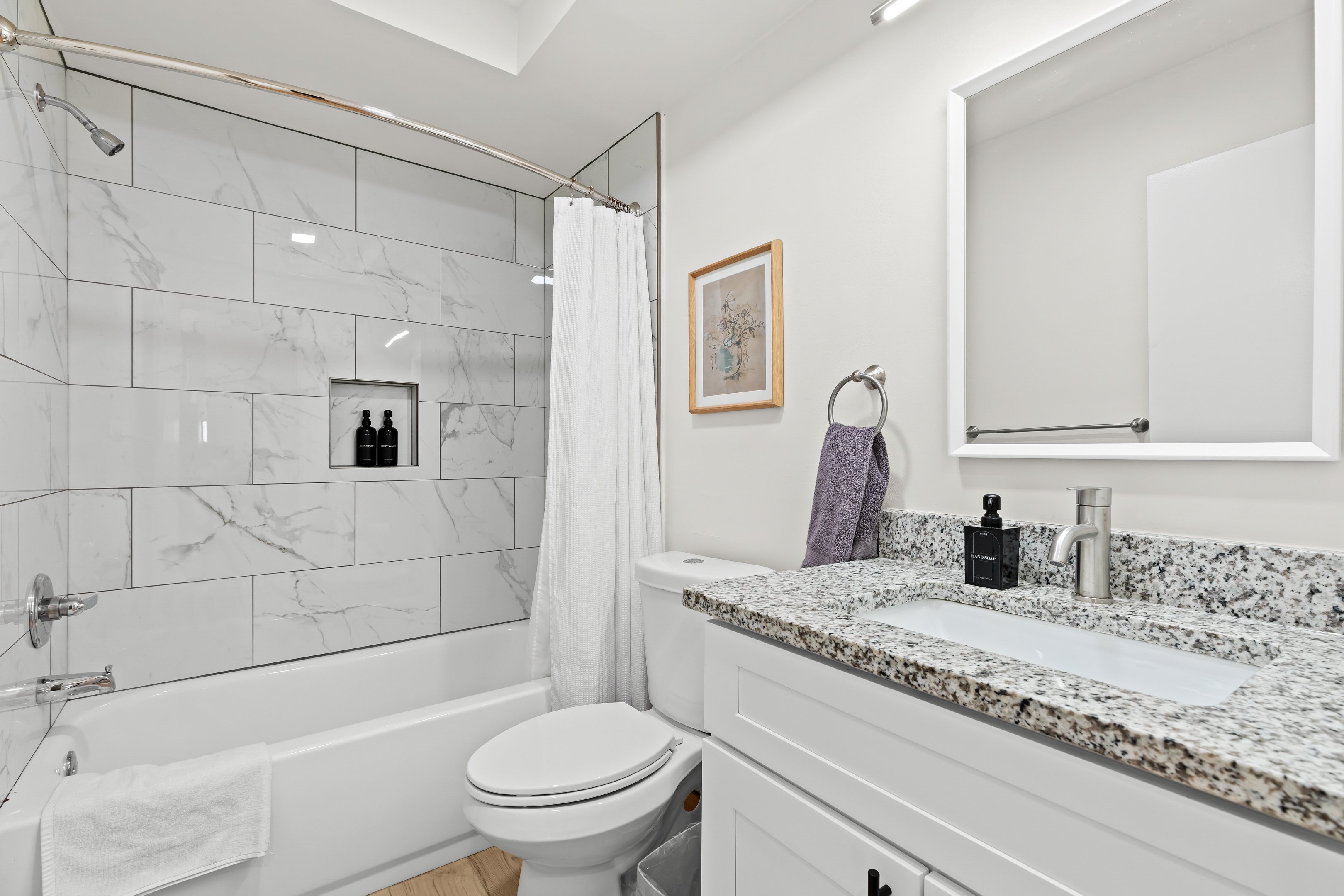 Spa-inspired bathroom featuring a sleek granite vanity, modern lighting, and a beautifully tiled shower with built-in niche.