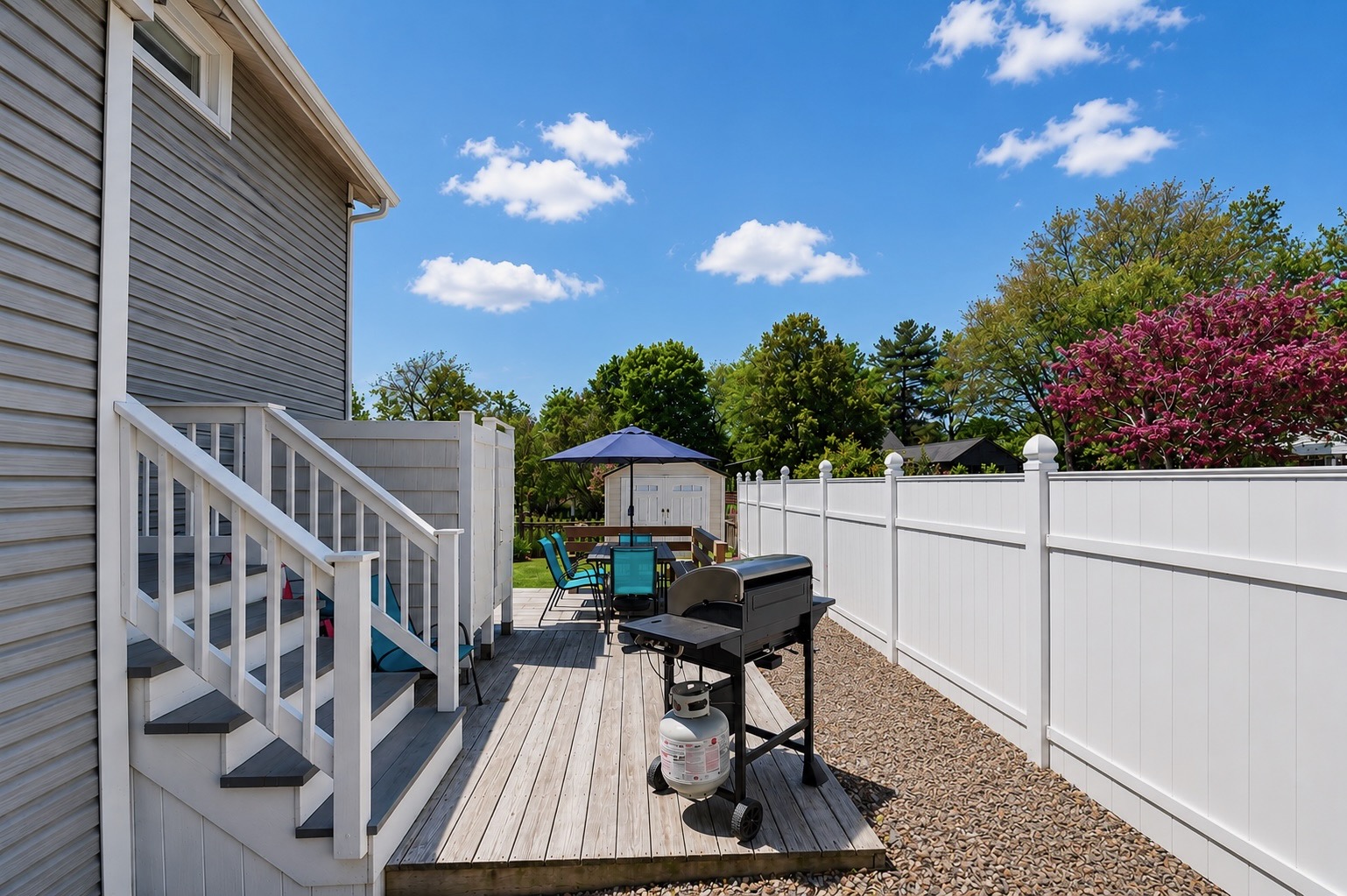 Backyard patio equipped with an outdoor shower, propane grill, and plenty of seating for the whole family to relax and unwind.