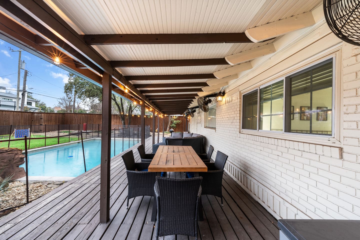 Covered patio with pool views, string lights, and seating for the whole crew—perfect for grilling, games, and golden hour hangs.