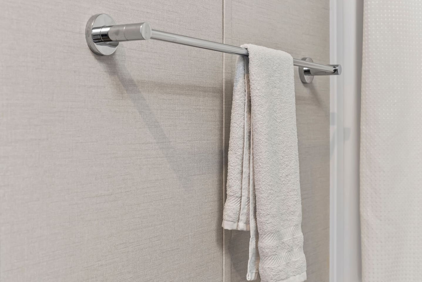 Fresh towels neatly arranged on a sleek towel bar, adding a clean and hotel-style touch.