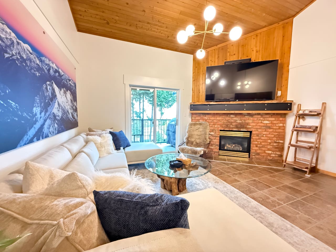 Main Living Area: An open-concept living room featuring vaulted cedar ceilings, a gas fireplace, and a large 78-inch Smart TV surrounded by alpine-inspired décor.