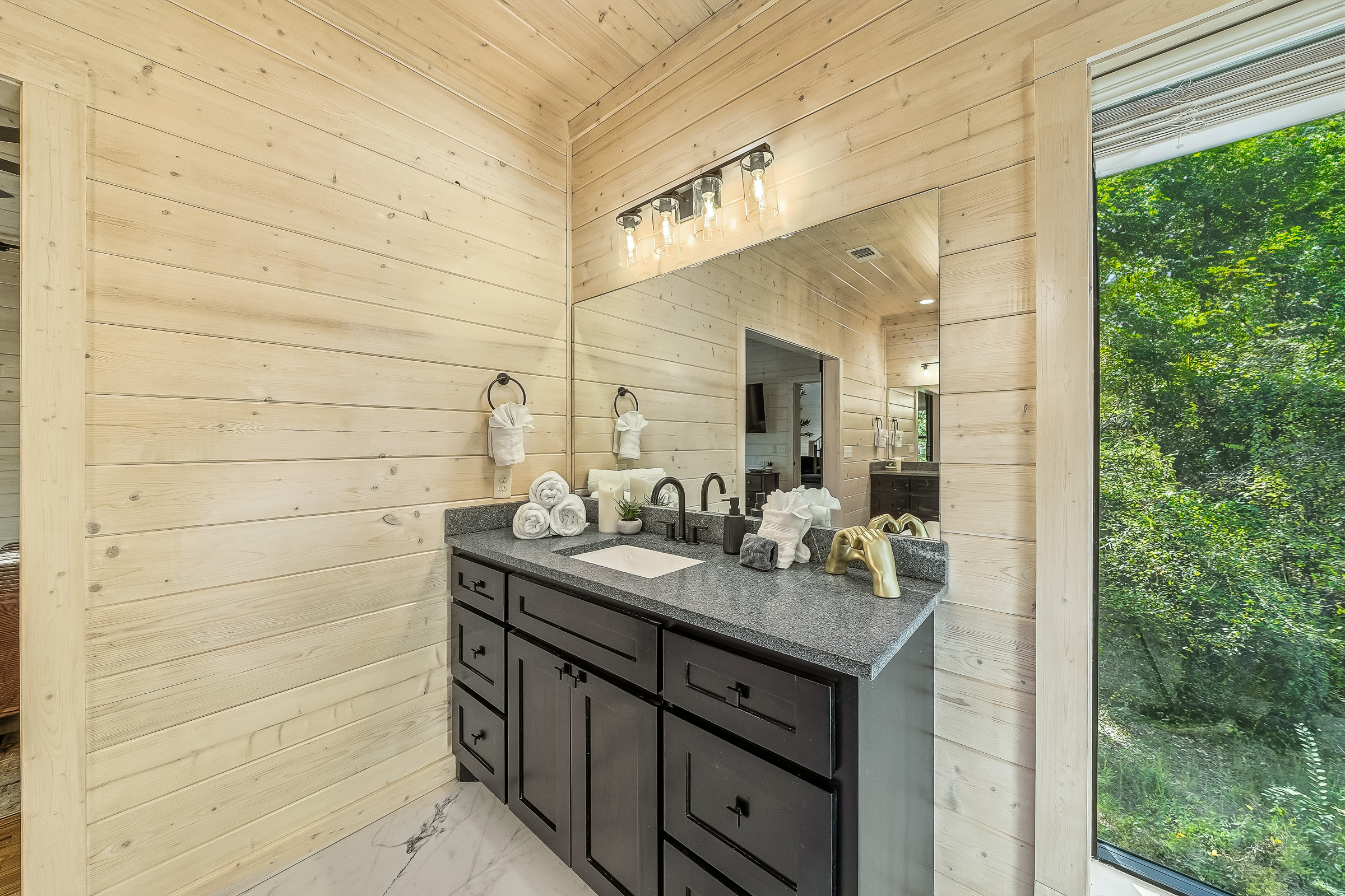 Bright vanity space with soft lighting and a beautiful view of the surrounding pines.