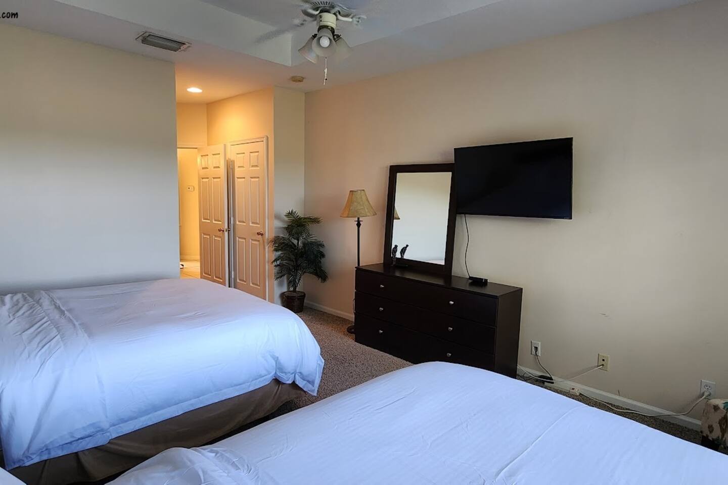 Spacious bedroom featuring two beds, dresser storage, TV, and plenty of room to unwind.
