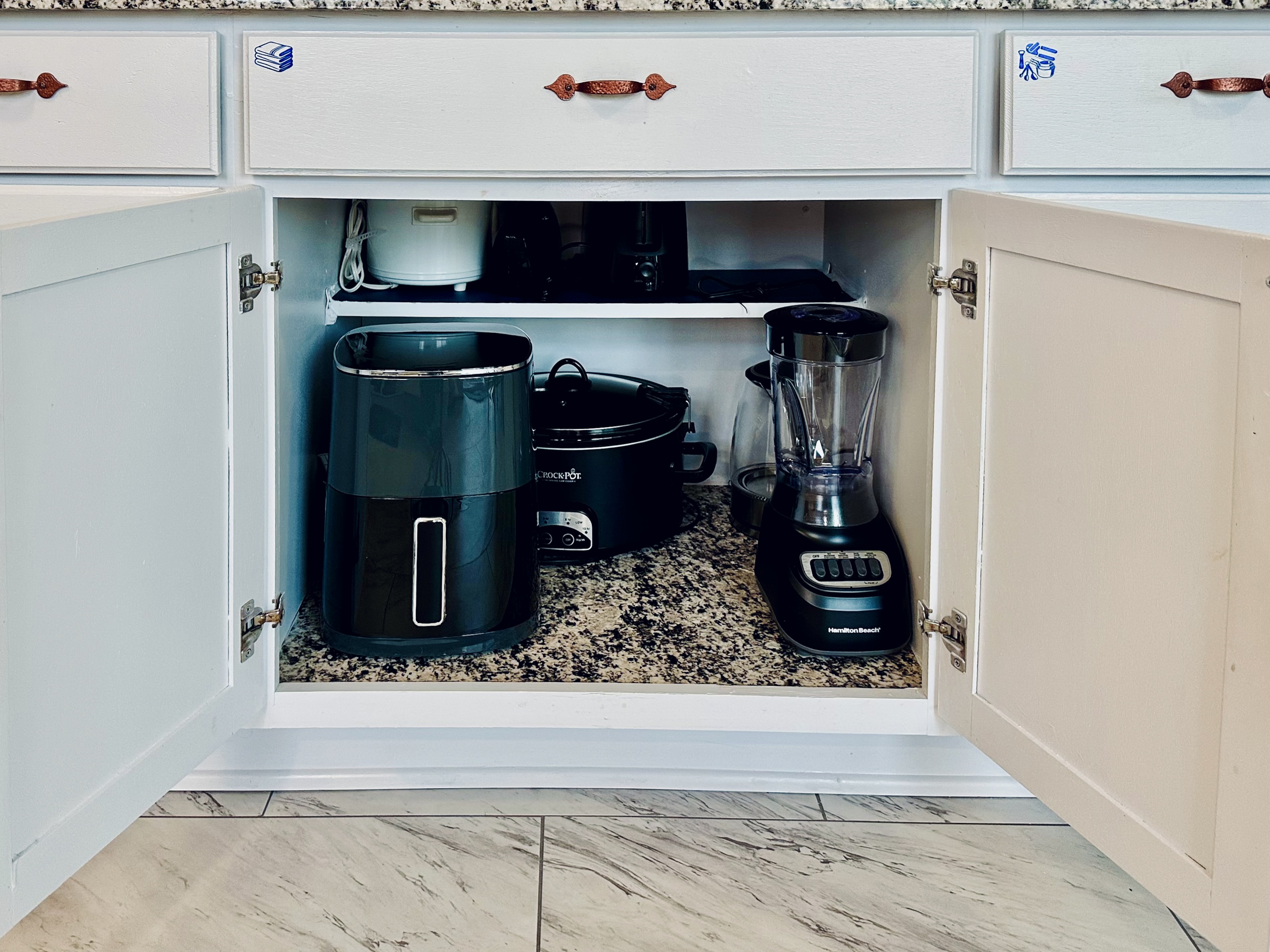 Dedicated kitchen cabinet stocked with small appliances, including an air fryer, large crock pot, small crock pot, hand mixer, toaster, electric kettle, and blender. Fully equipped for everyday cooking and extended stays.