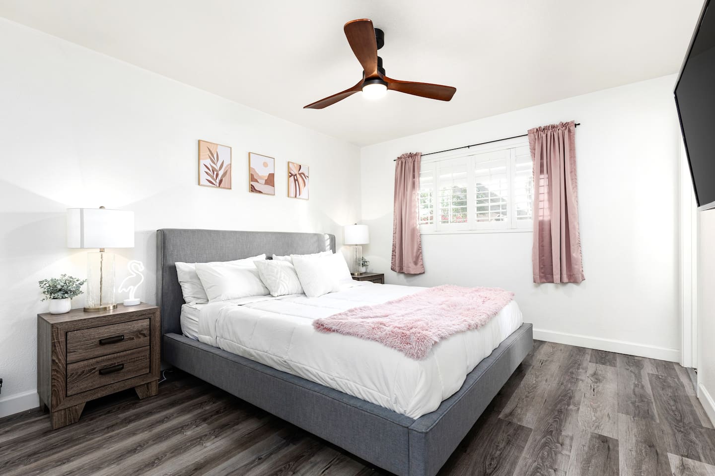 Sleep soundly in this serene king room featuring a padded headboard, stylish artwork, and natural light through plantation shutters.

