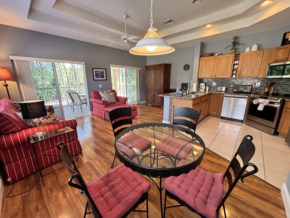 Bright open-concept living and dining area with wood-look flooring, comfortable seating, and a fully equipped kitchen.