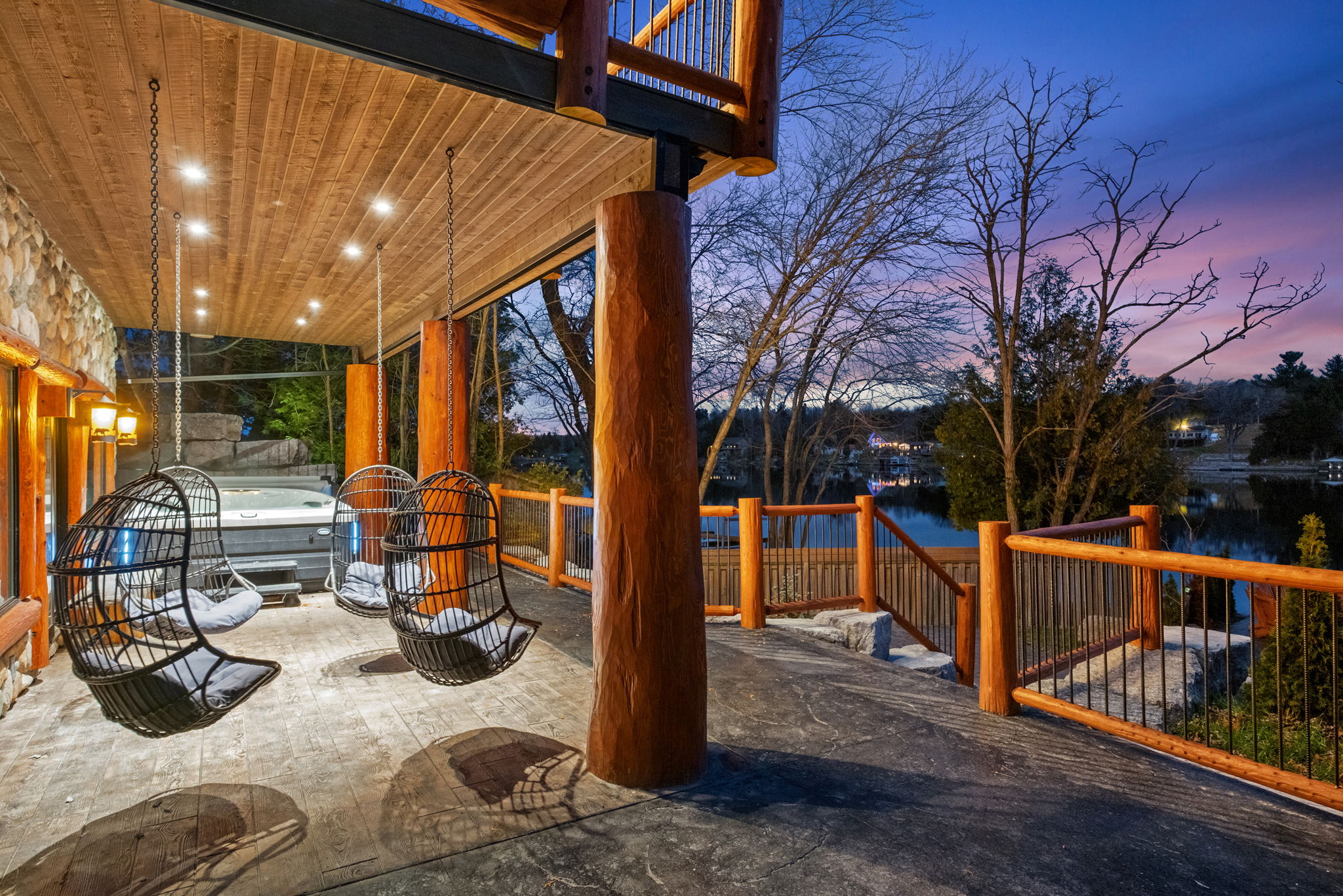 Cozy lakeside relaxation zone featuring hanging egg chairs, ambient lighting, and panoramic water views.