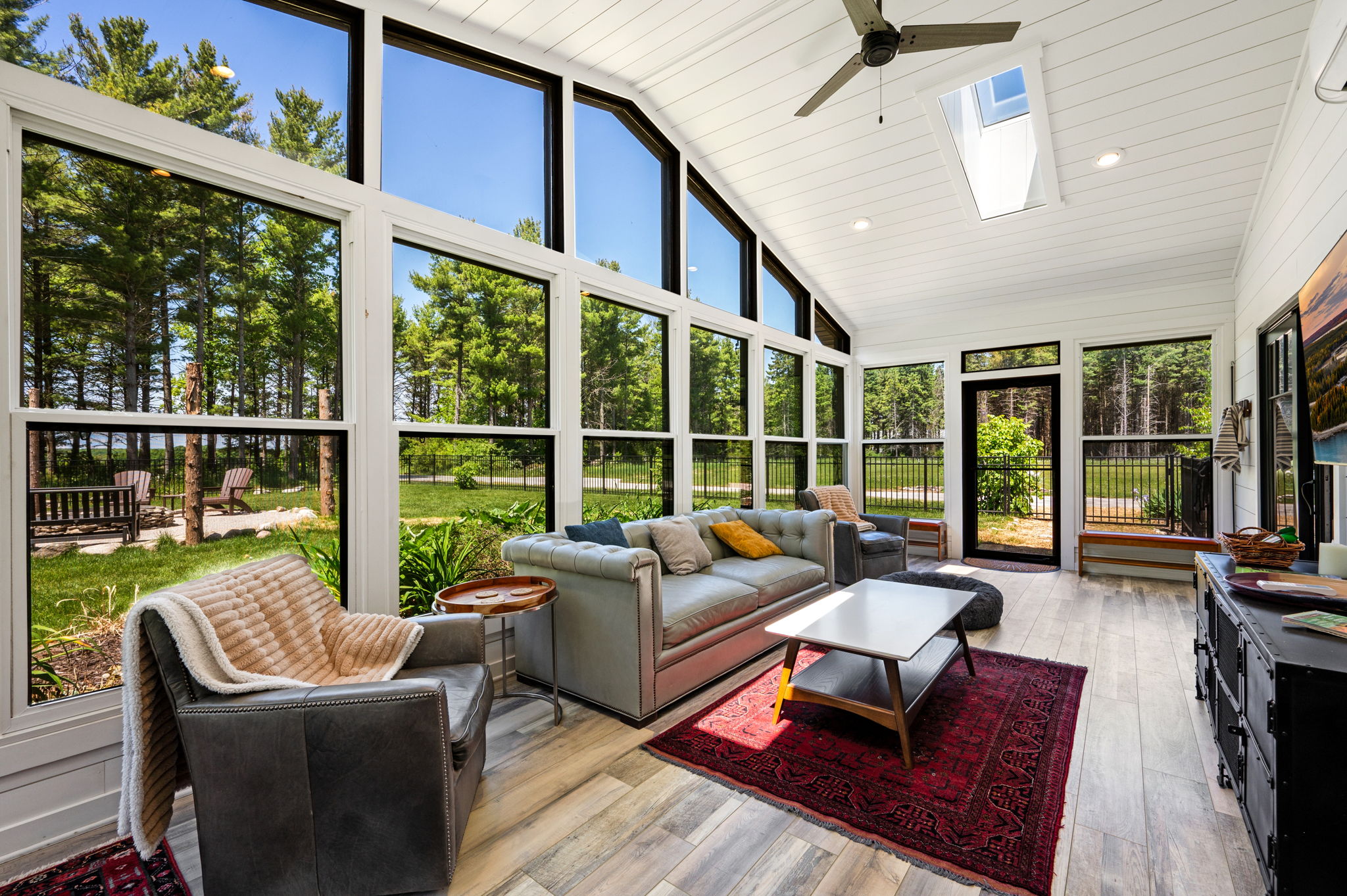 Soak up natural light in the sunroom's inviting seating area, where wraparound windows bring the outdoors in from every angle.