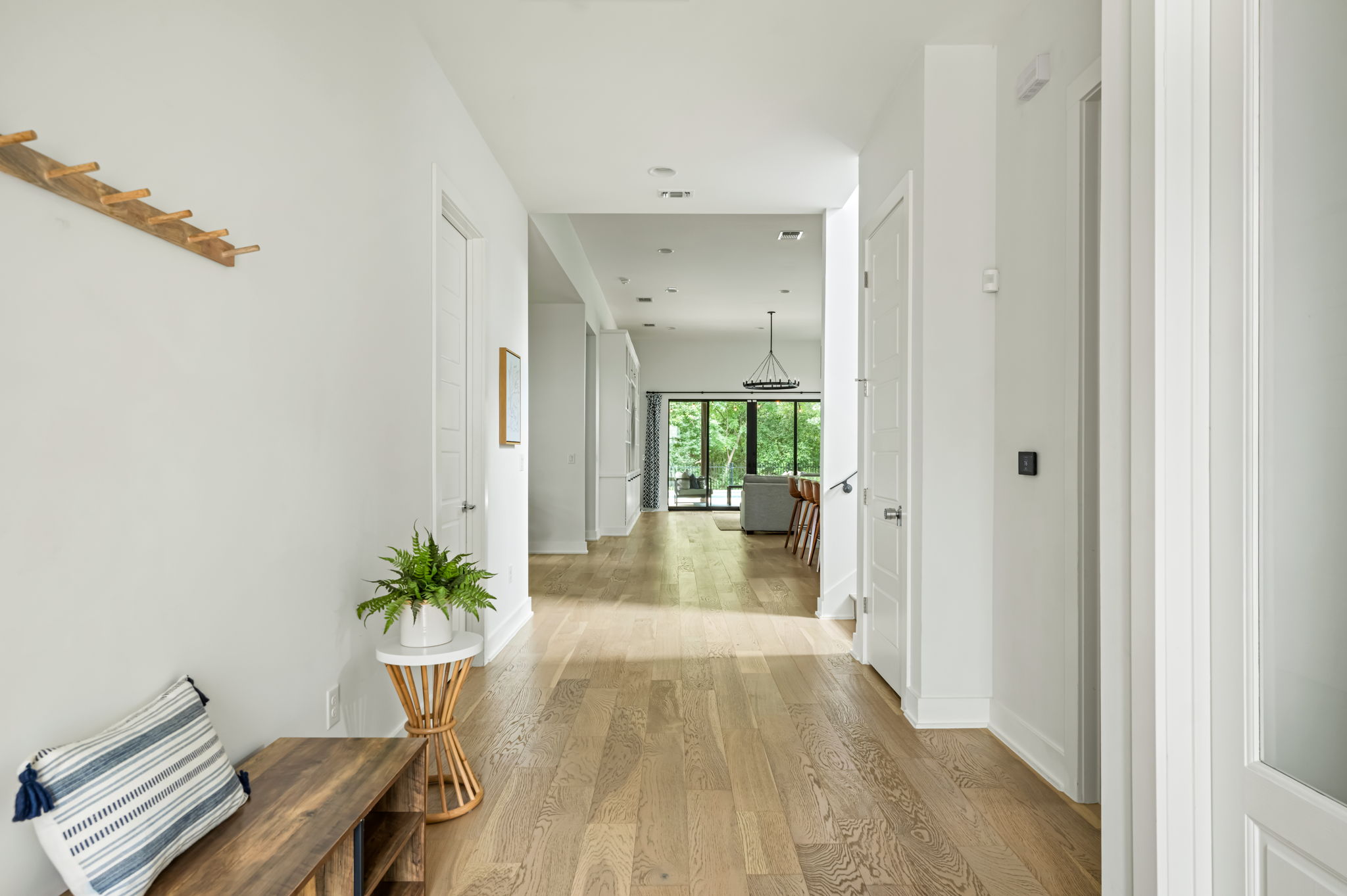 Welcoming entryway with rich hardwood floors, wall-mounted coat hooks, and stylish console table — the perfect drop zone for luggage and shoes.
