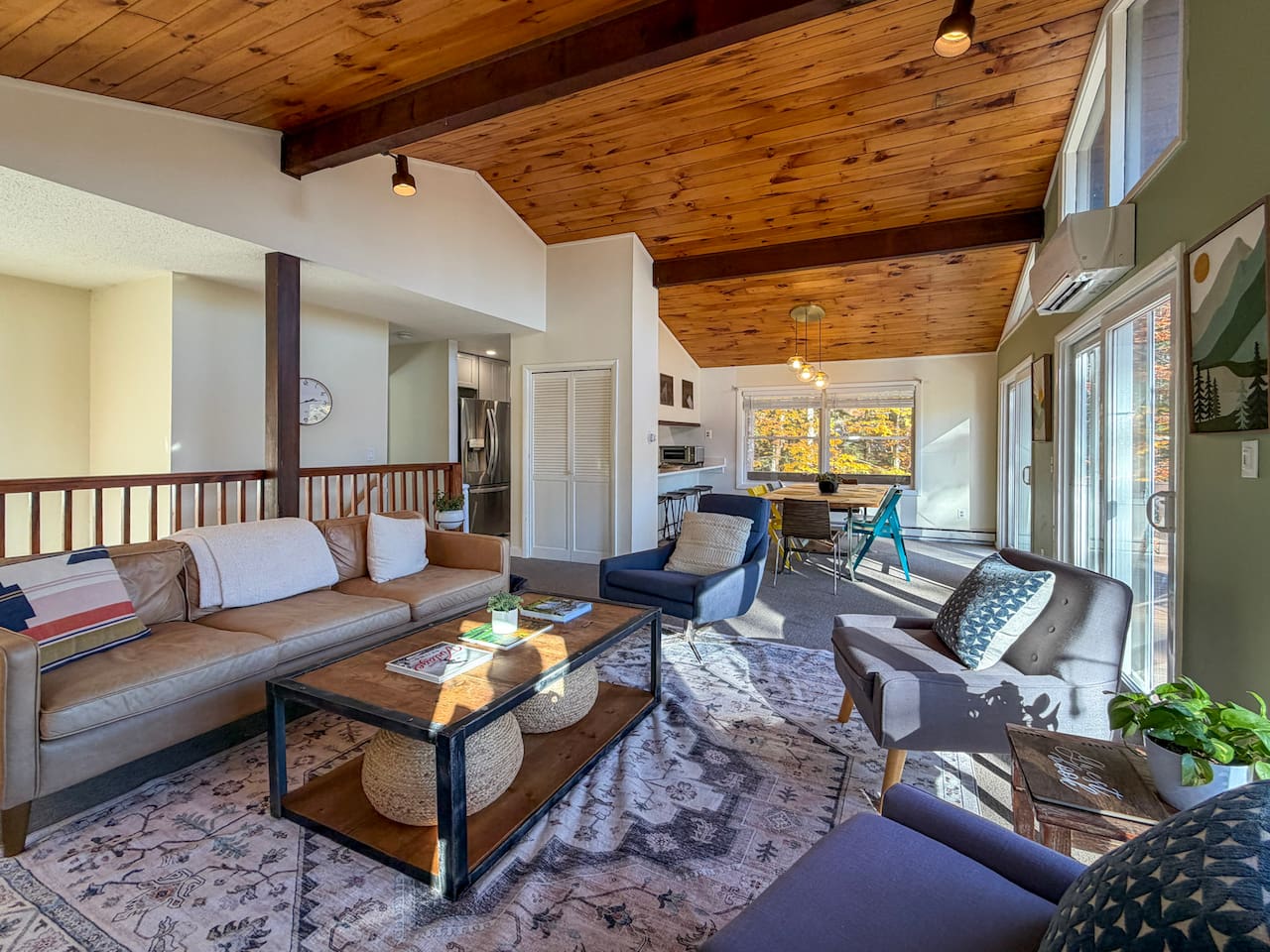 The open plan living and dining area on the second floor adjoins a galley kitchen. Sliding doors open up to a deck with a grill, dining set, and fire pit with Adirondack chairs.