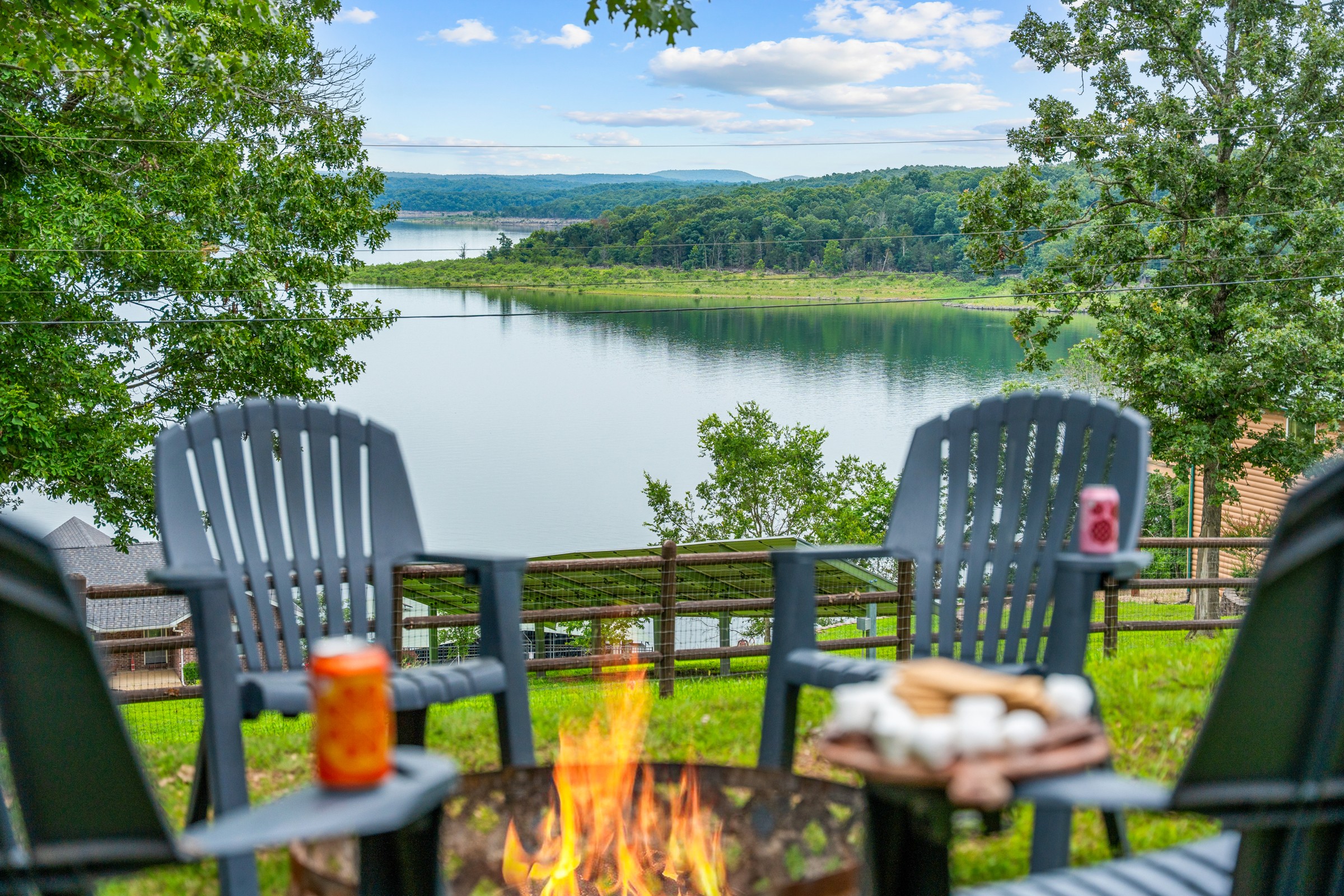 Fire pit with Adirondack chairs facing the lake view. S'mores on the armrest and the water out front.