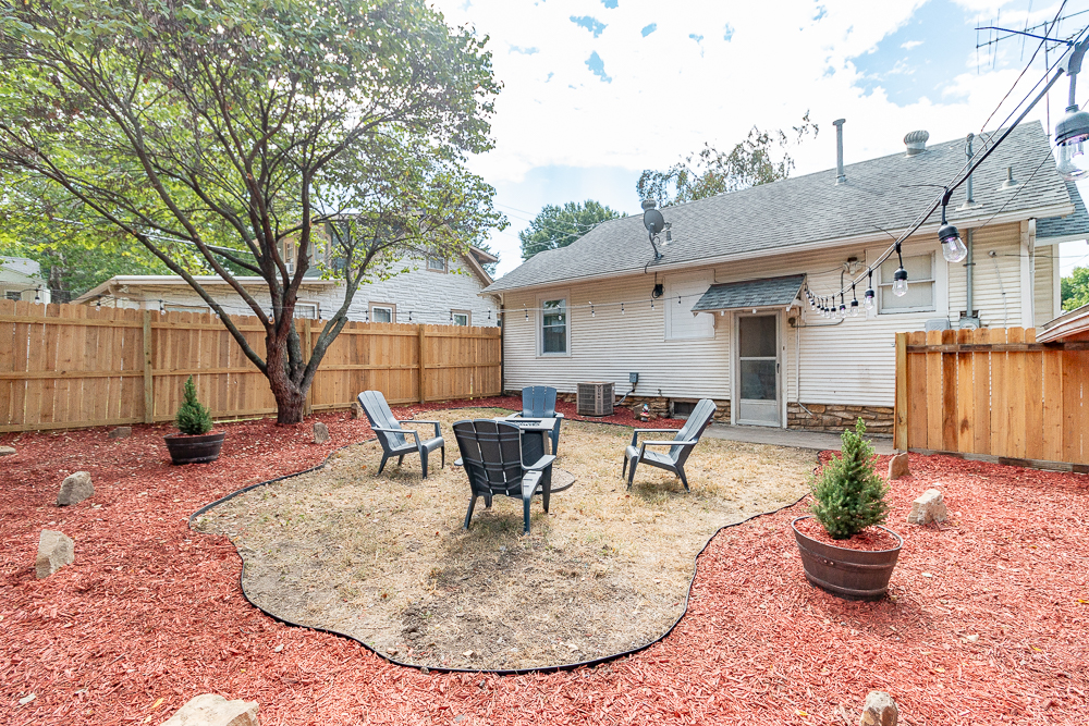 Unwind in the private fenced backyard with a cozy fire pit and string lights.