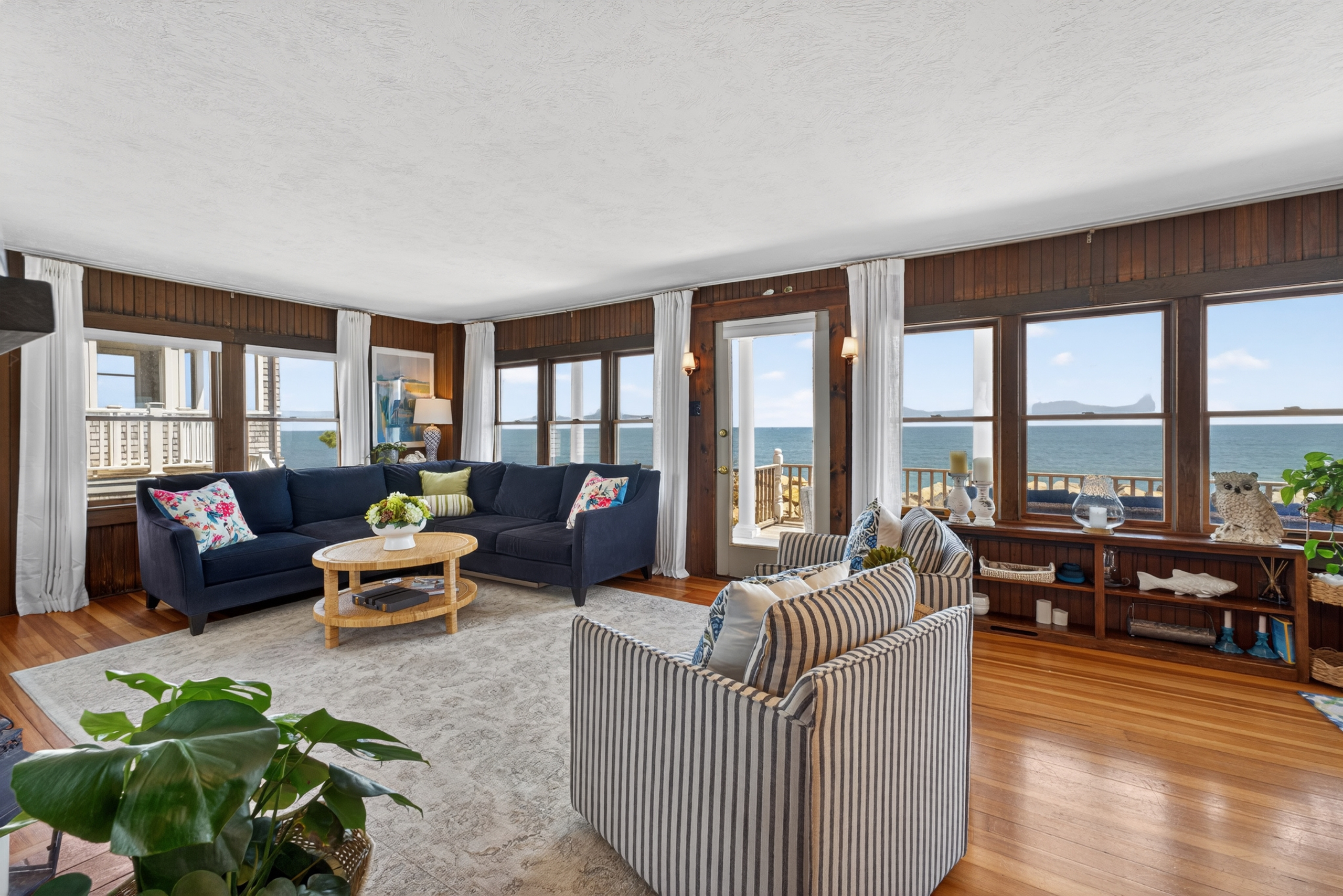 Bright coastal living space with panoramic ocean views, cozy seating, and direct access to the private deck, perfect for relaxing to the sound of the waves. 🌊