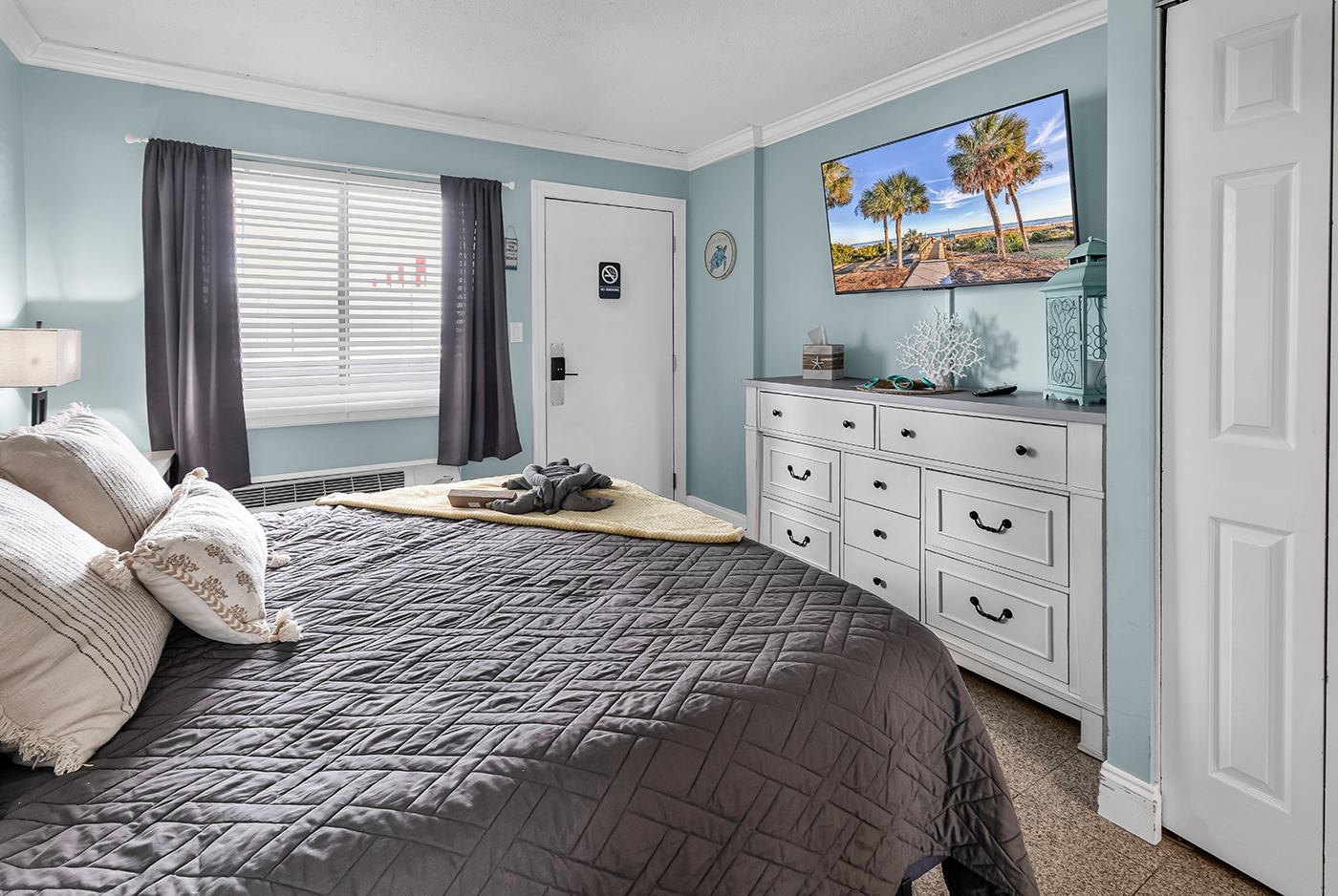 Bedroom with king bed, wall-mounted TV, window with natural light, and blackout curtains for a restful night's sleep