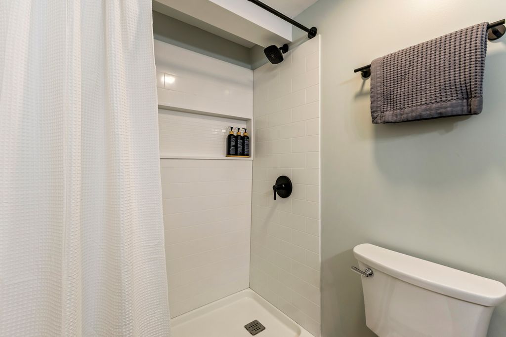 Full bathroom along the hallway with large shower, vanity, and storage.