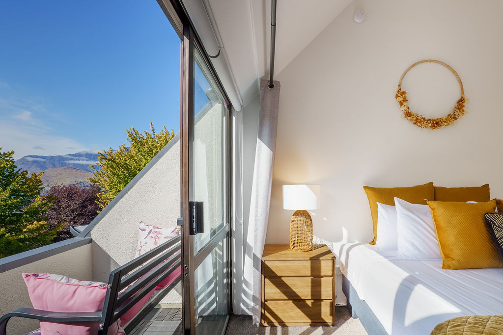 The balcony doors frame Fernhill’s mountain outlook, giving this upstairs king-single bedroom a bright alpine feel.