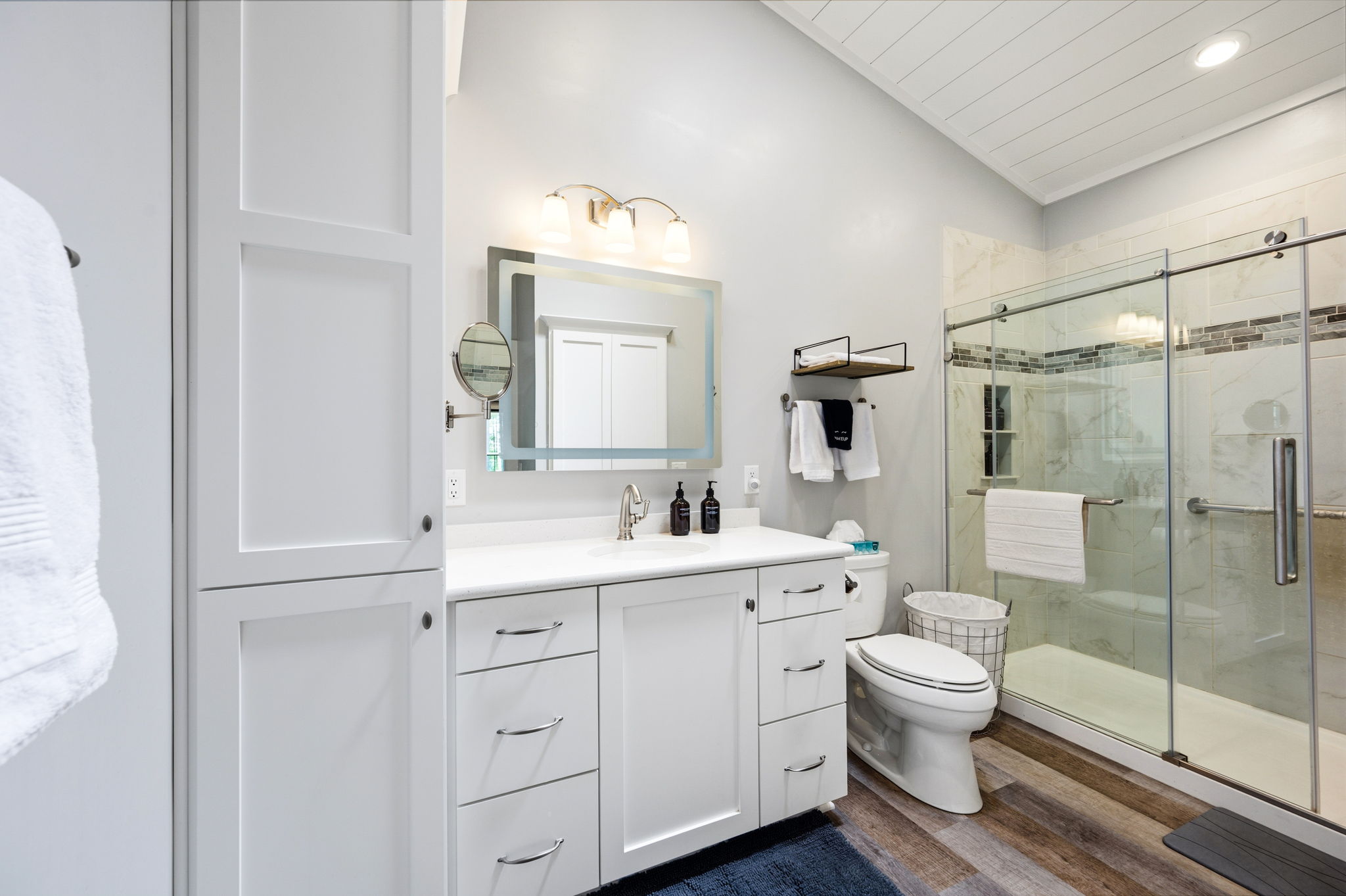 Refresh in the spa-like en suite bath, featuring a walk-in glass shower with marble-look tile, a quartz-topped vanity, and a private toilet.