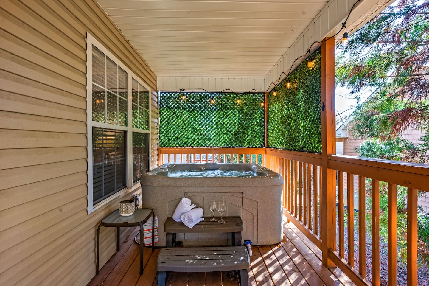 Unwind on the private covered deck with a bubbling hot tub, cozy string lights, and plenty of privacy—perfect for relaxing day or night.