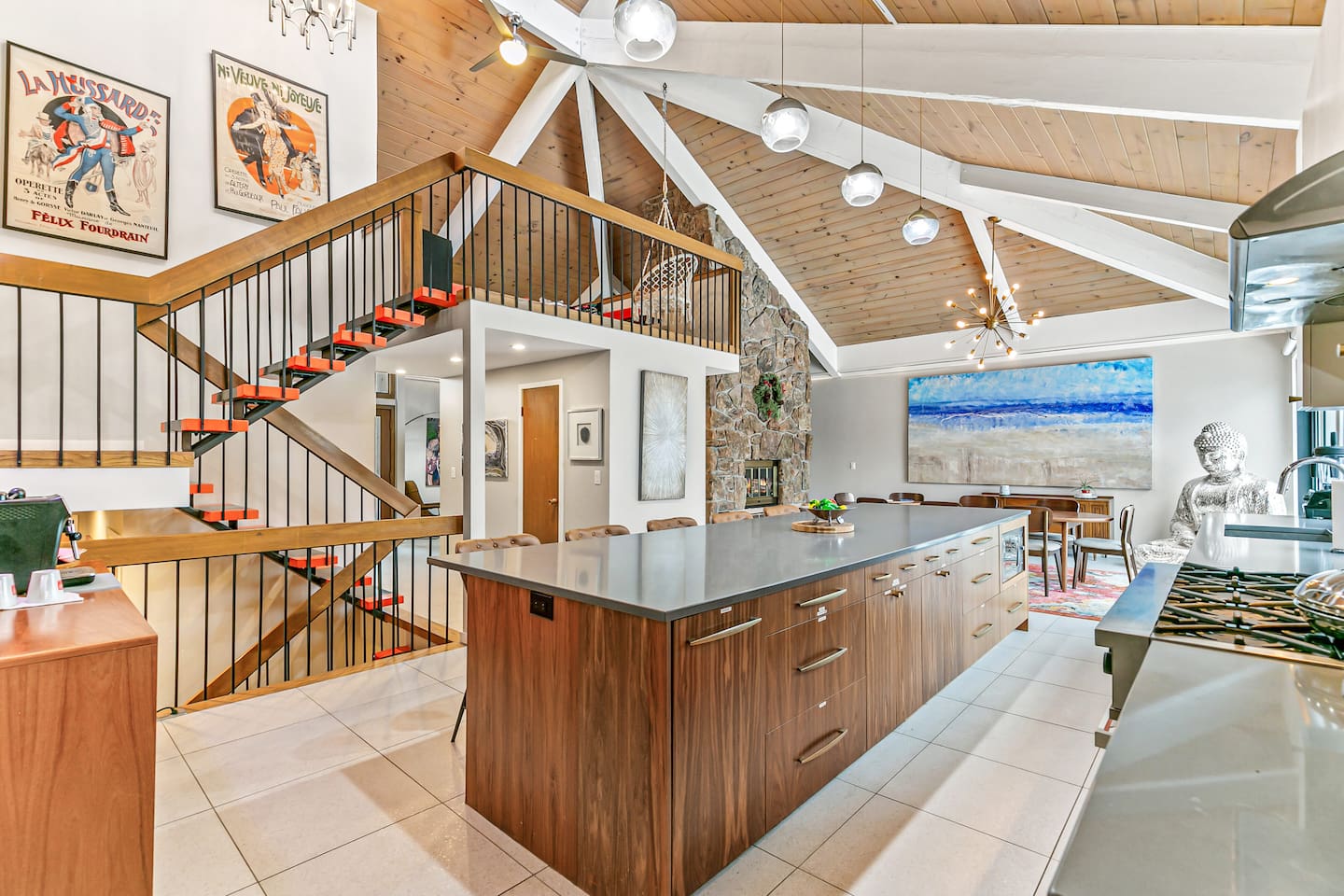 The kitchen is fully equipped with modern appliances, a Mid-Century Modern interior design, a large fridge, freezer, and ample storage. It boasts a spacious layout and a 16 ft island table, with convenient access to the outdoor area.
