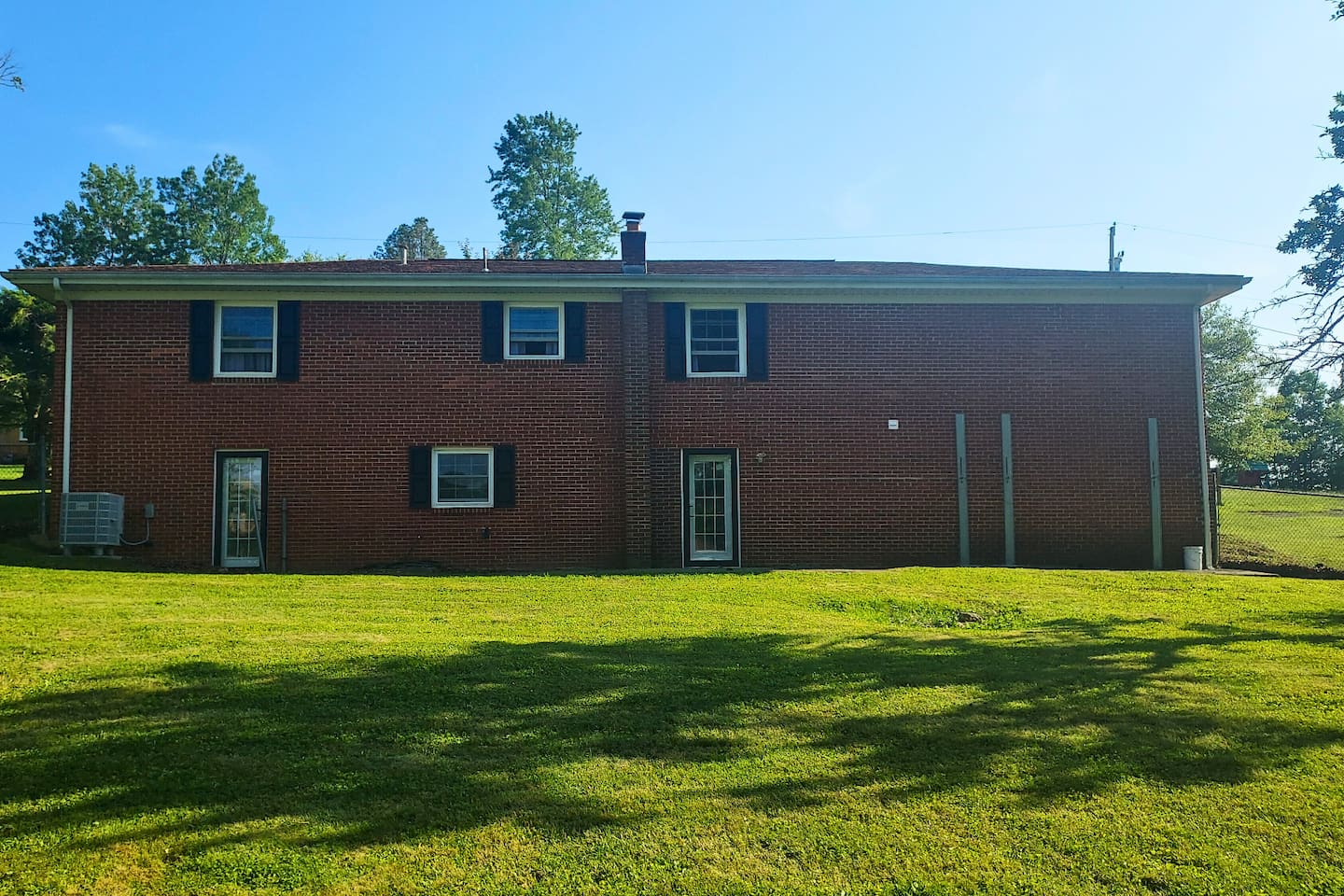  The back of this brick ranch has a stately, welcoming feel, with a cozy little patio nestled against the house and a view over the fully fenced, chain-link yard—perfect for peaceful mornings or playful afternoons.