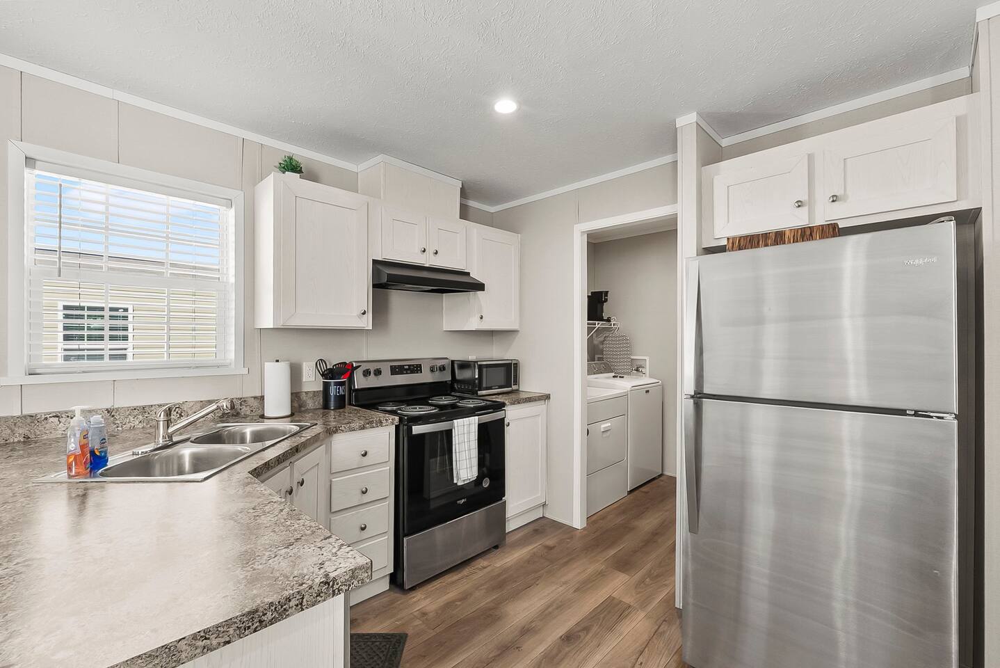 Bright kitchen with stainless steel appliances and nearby laundry access for added convenience.