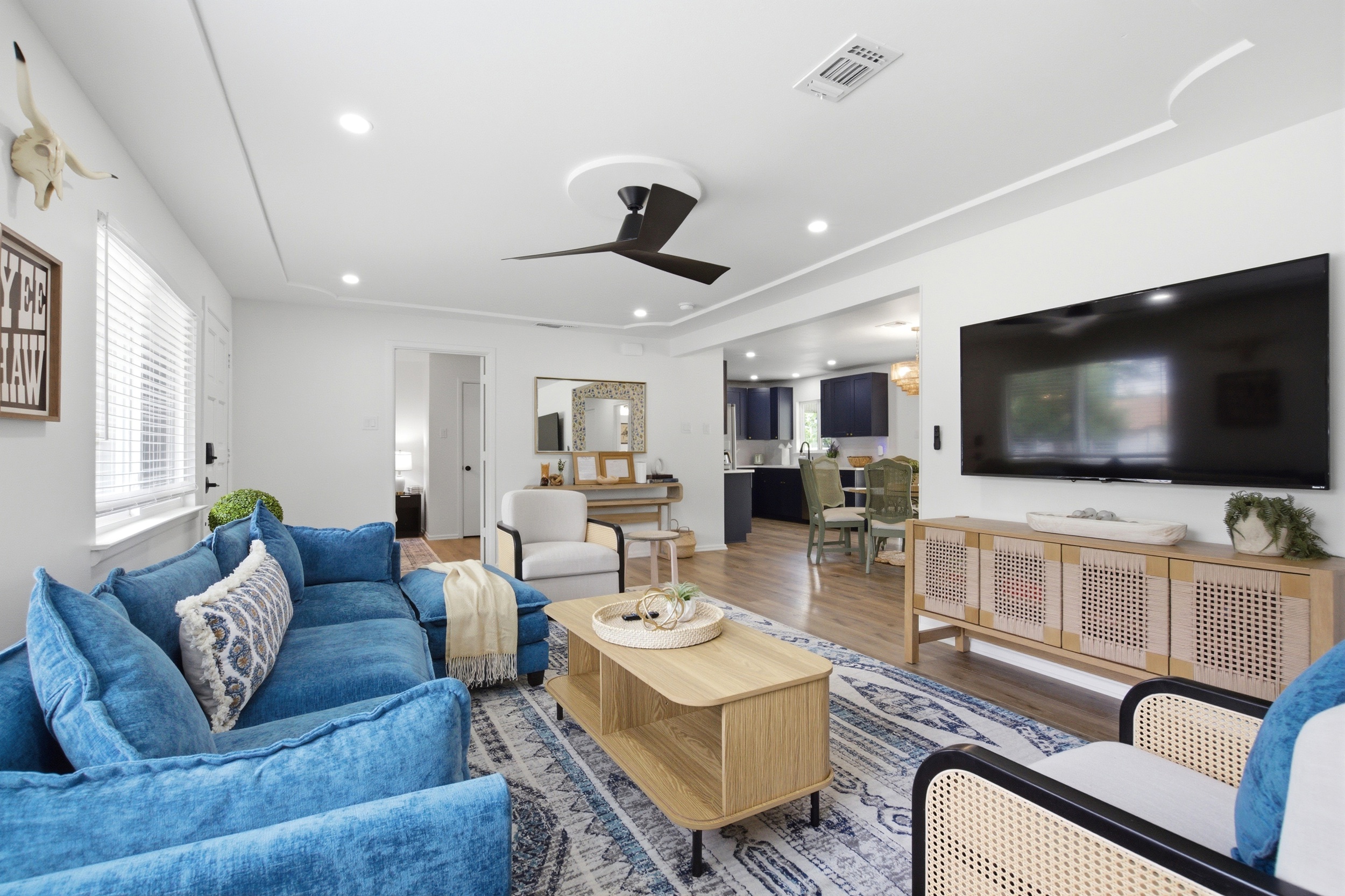 Open-Plan Living and Dining Room with 65 inch Smart TV, comfortable lounge seating, and modern chandelier. Ideal for group gatherings and Arlington event weekends.

