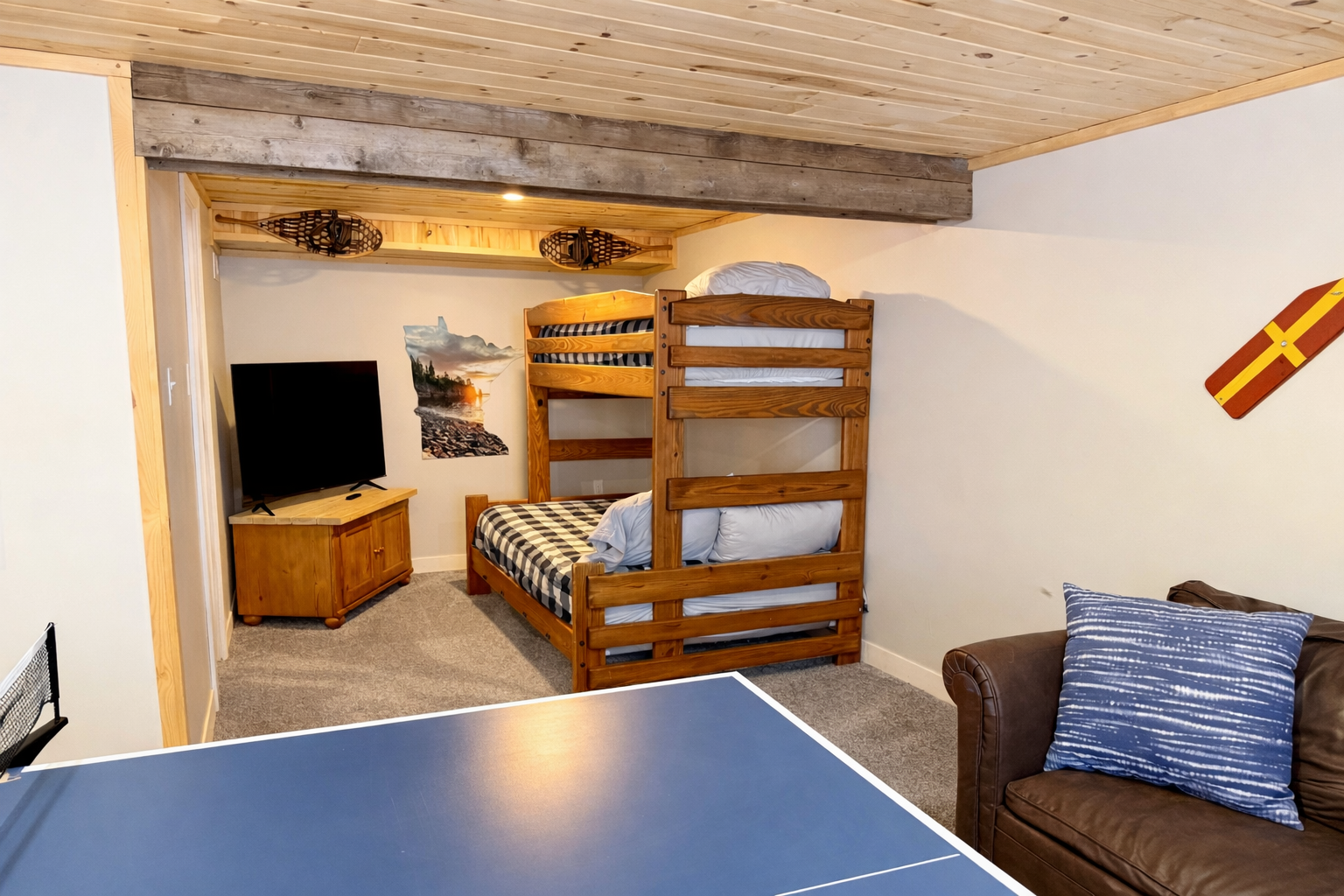 Cozy basement bunk room featuring a comfortable bunk bed, couch, and TV. Perfect for kids, teens, or extra guests. A relaxed hangout space that’s great for movie nights and unwinding after a full day exploring Black Beach and Tettegouche State Park. 