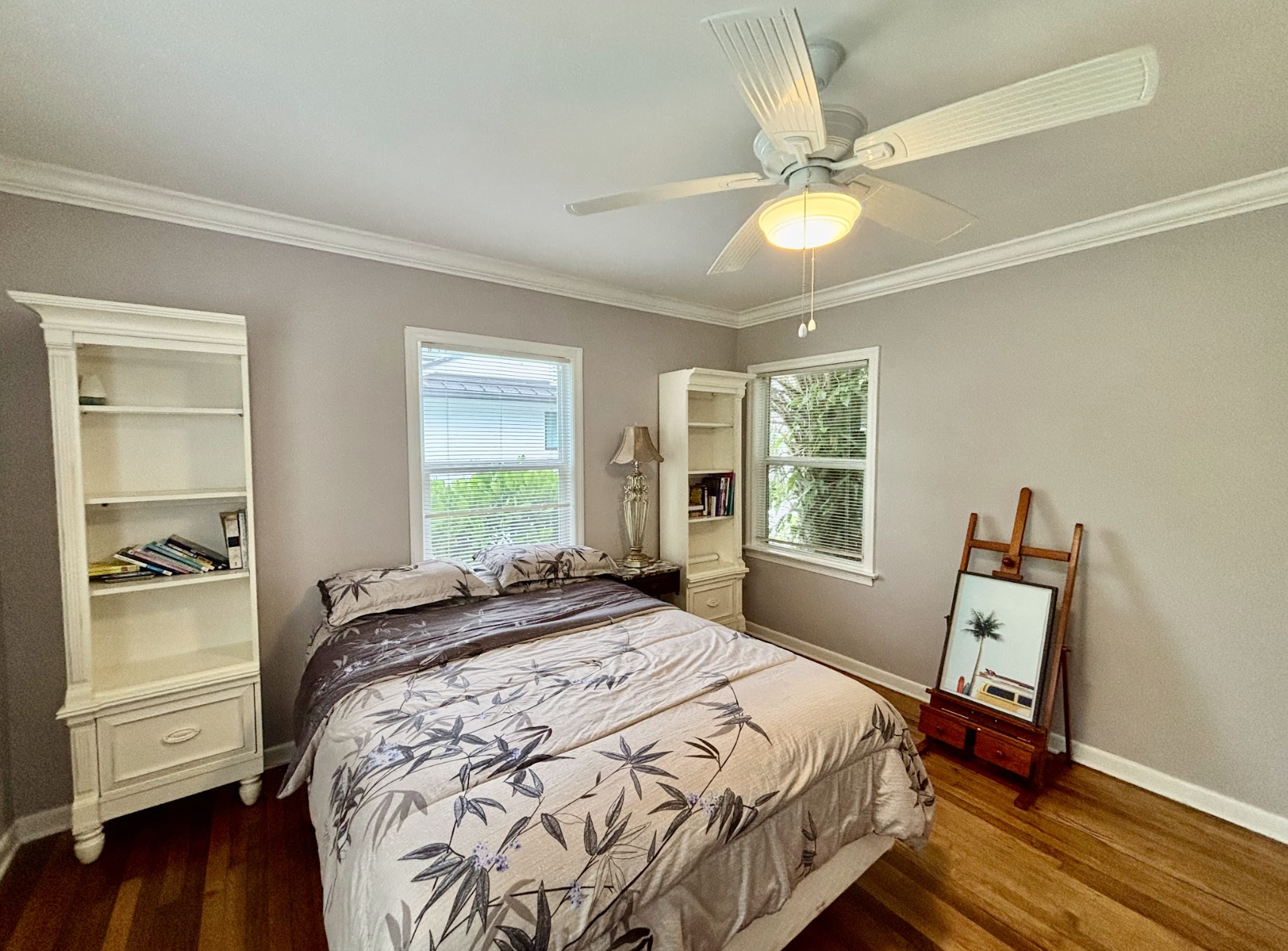 The second bedroom features a queen-zied bed and a stylish painter's floor stand.