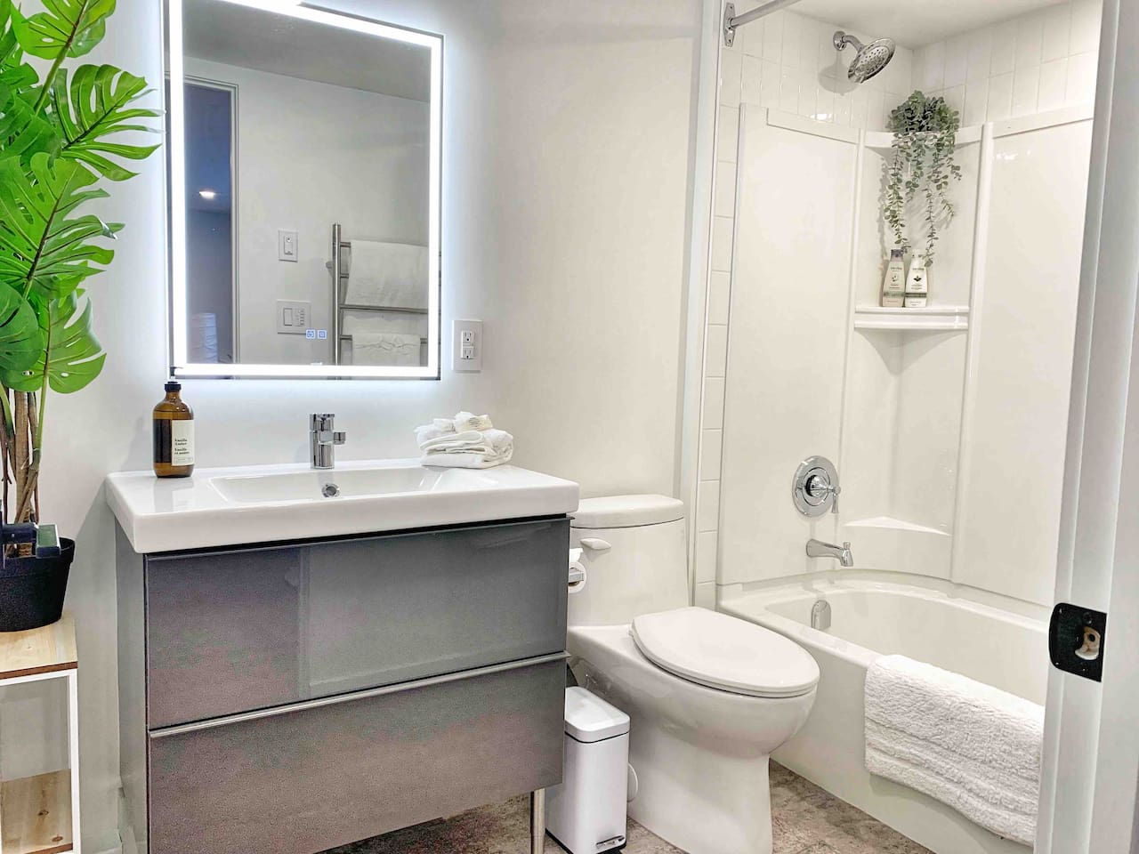 Main bathroom with modern vanity, illuminated mirror, and clean, minimalist finishes.