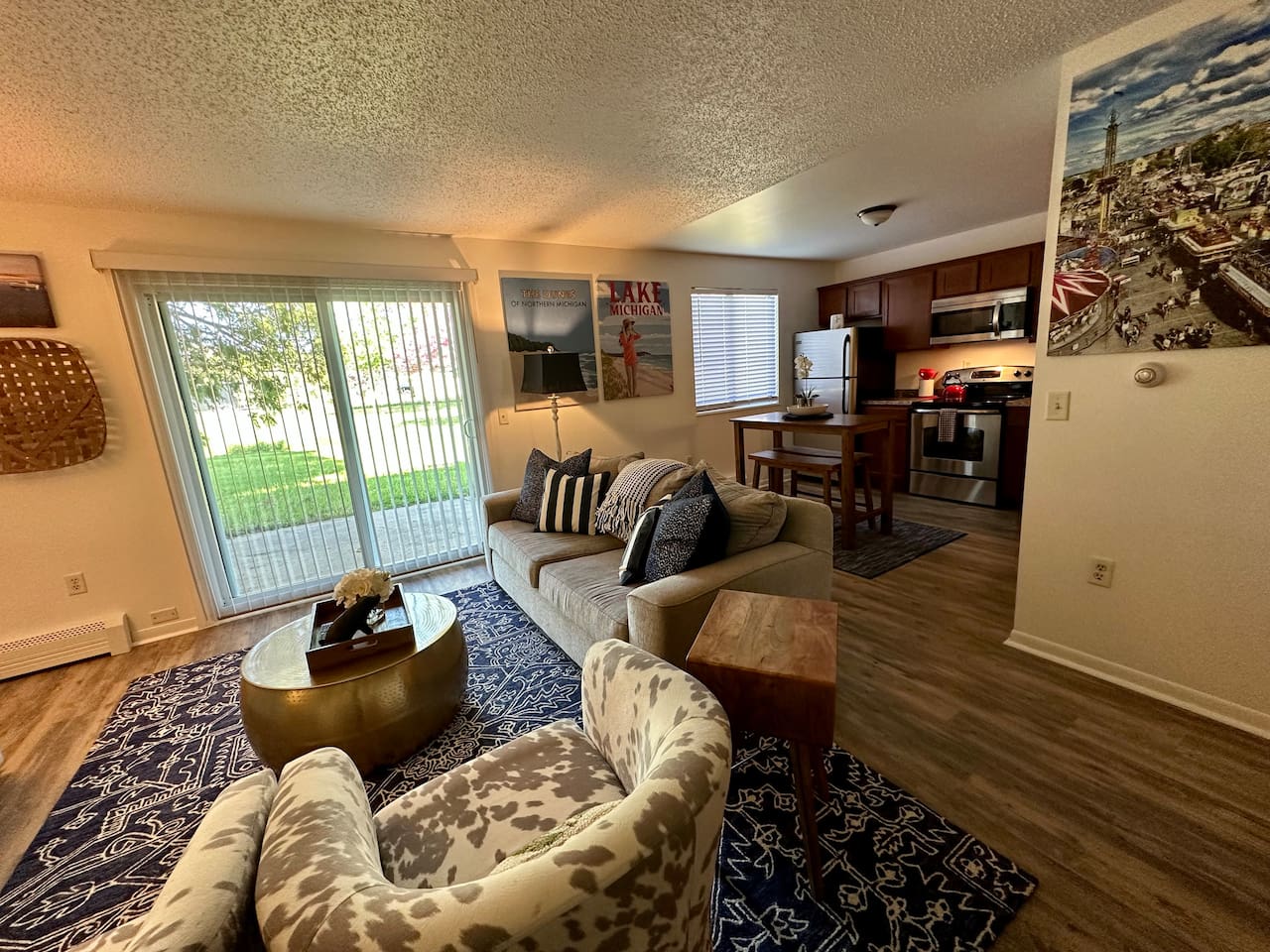 Enjoy a cozy, open-concept space with a comfy sofa, bold decor, and a fully stocked kitchen featuring stainless appliances. A bistro-style dining table, natural light, and charming Michigan art make this the perfect retreat for work or play.